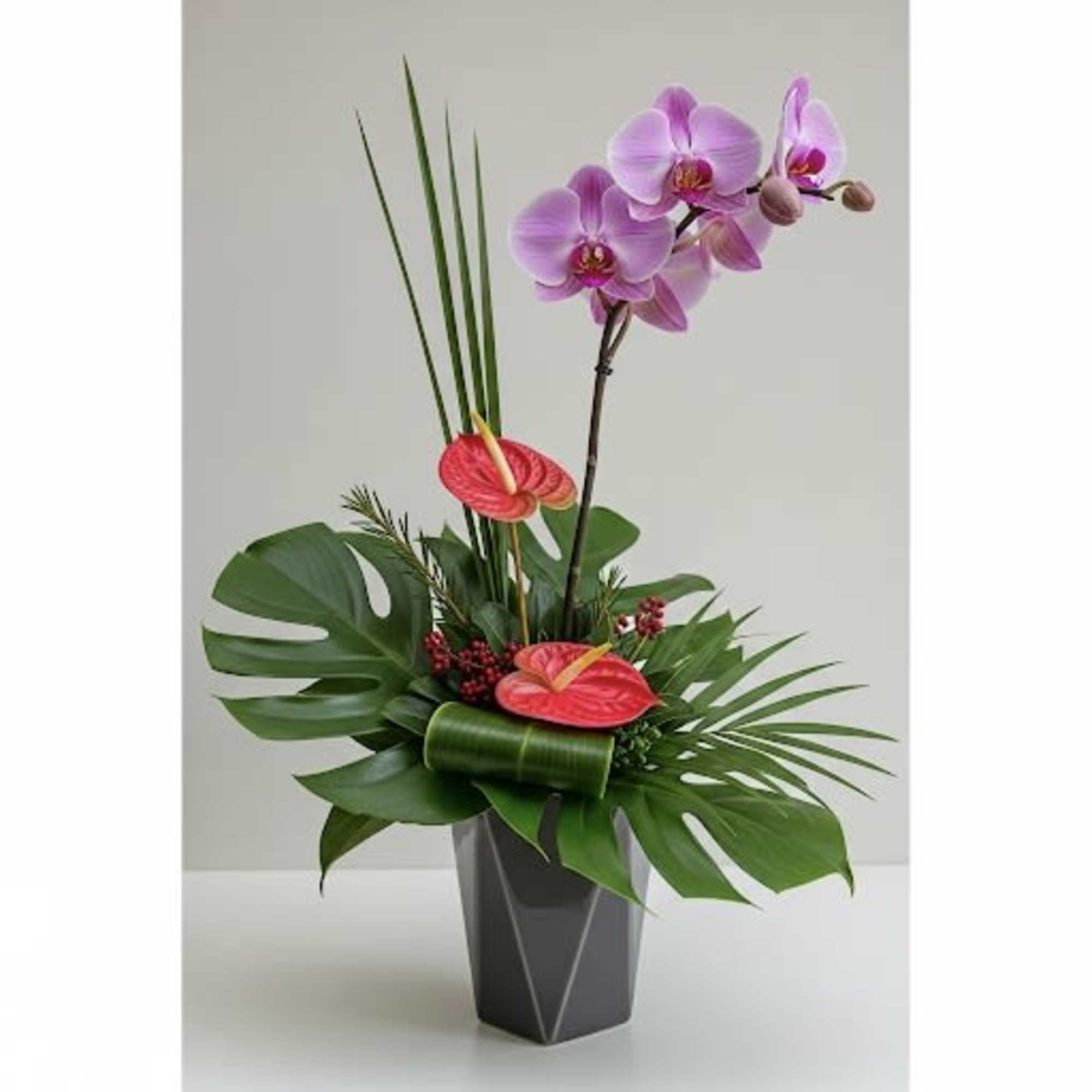 Tropical arrangement with pink orchids and red anthuriums in a dark vase