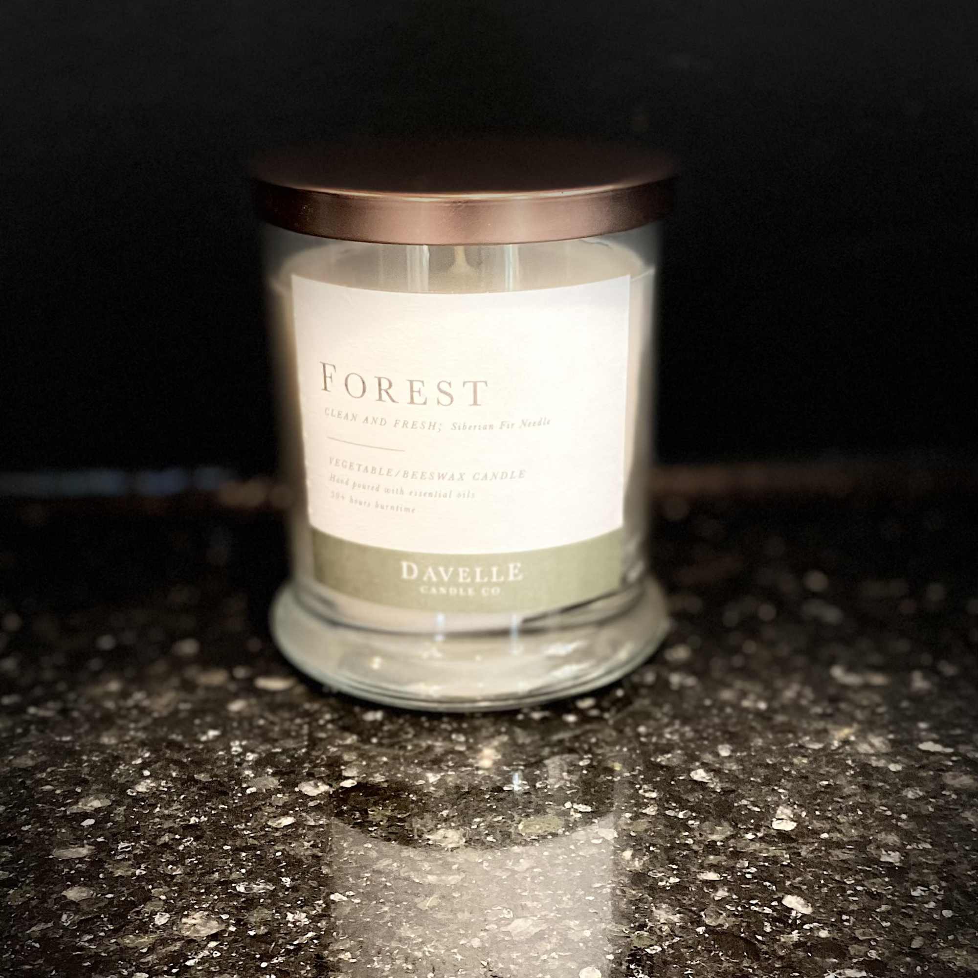 A scented candle in a glass jar with a copper lid