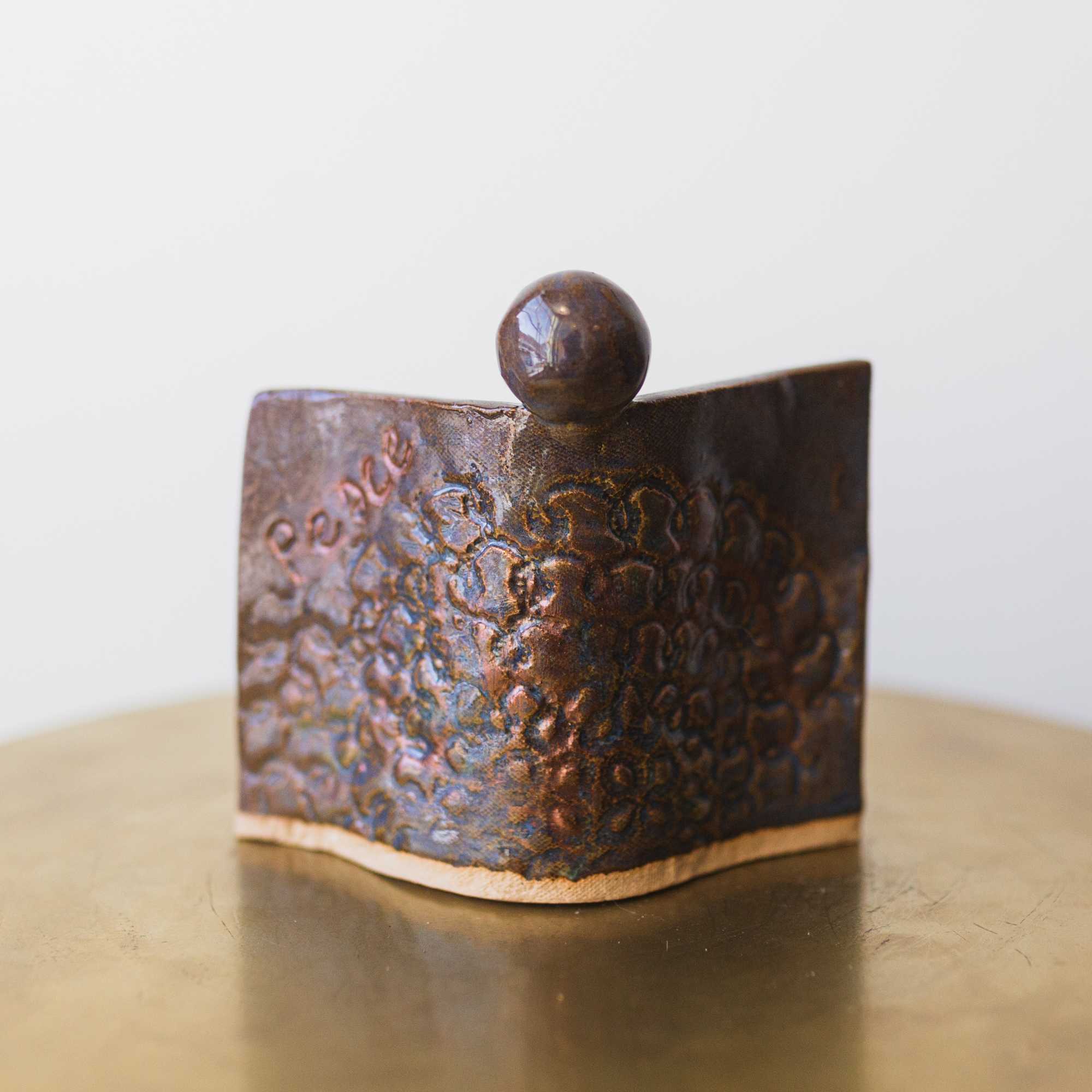 Small hammered metal decorative container with a round knob on top