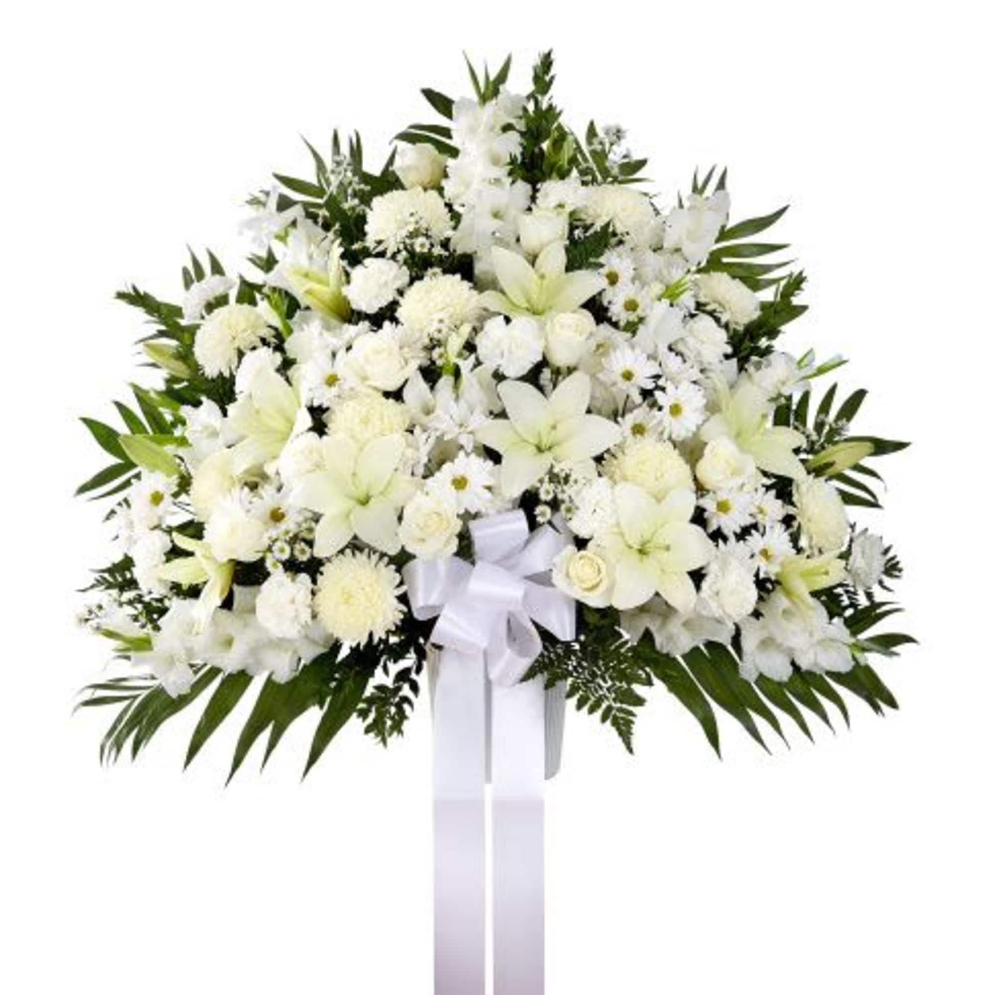Standing white funeral spray with lilies, roses, and chrysanthemums accented with a white bow.