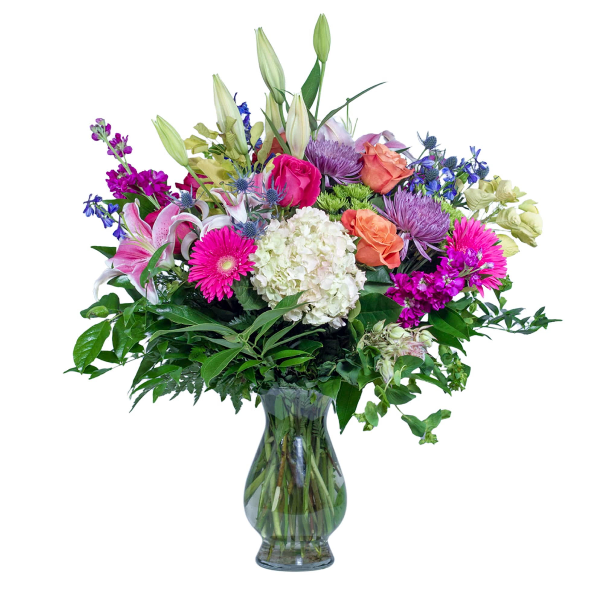 Tall mixed bouquet of pink lilies, roses, gerberas and other flowers in a clear glass vase