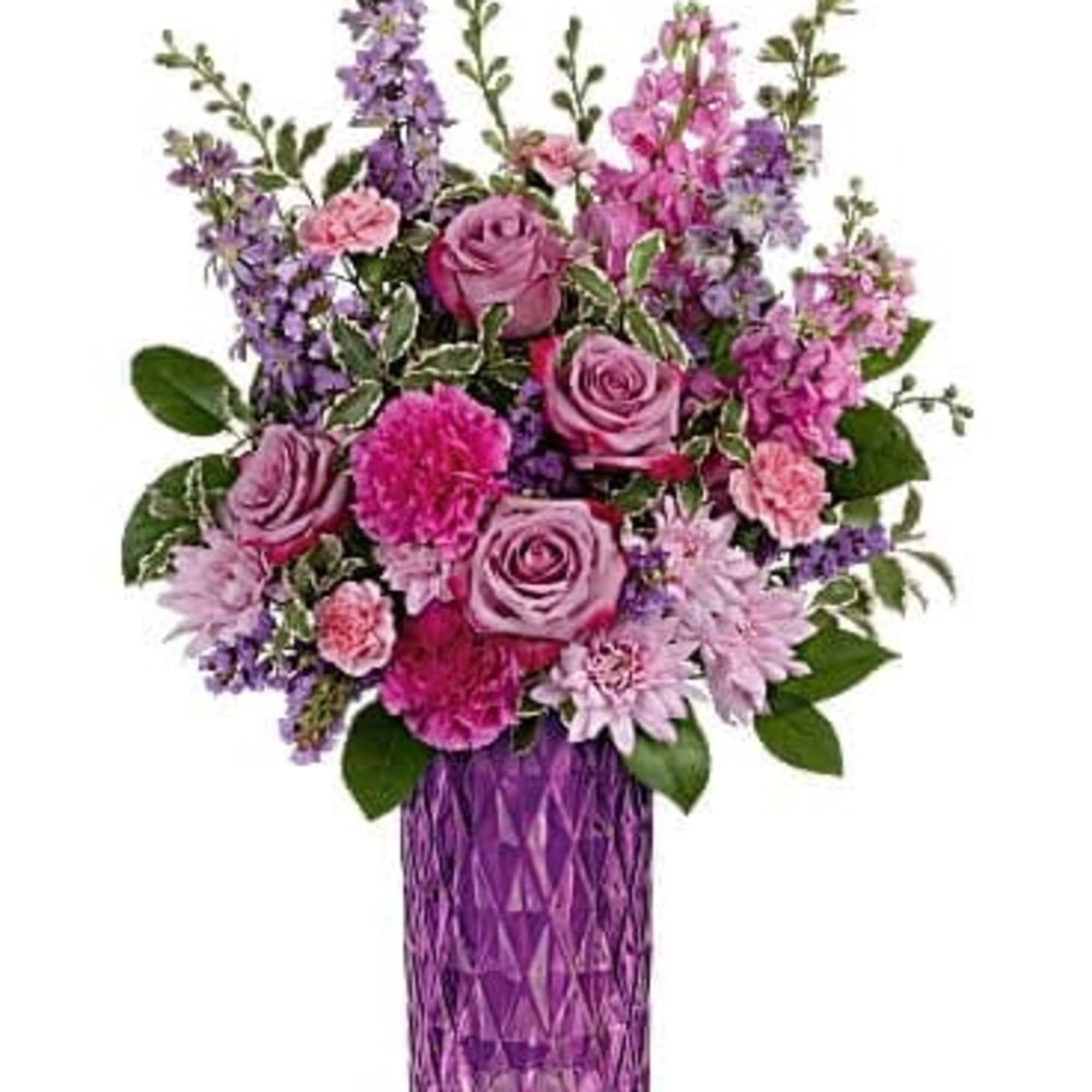 Tall arrangement of pink and purple roses, carnations, and mums in a faceted purple glass vase