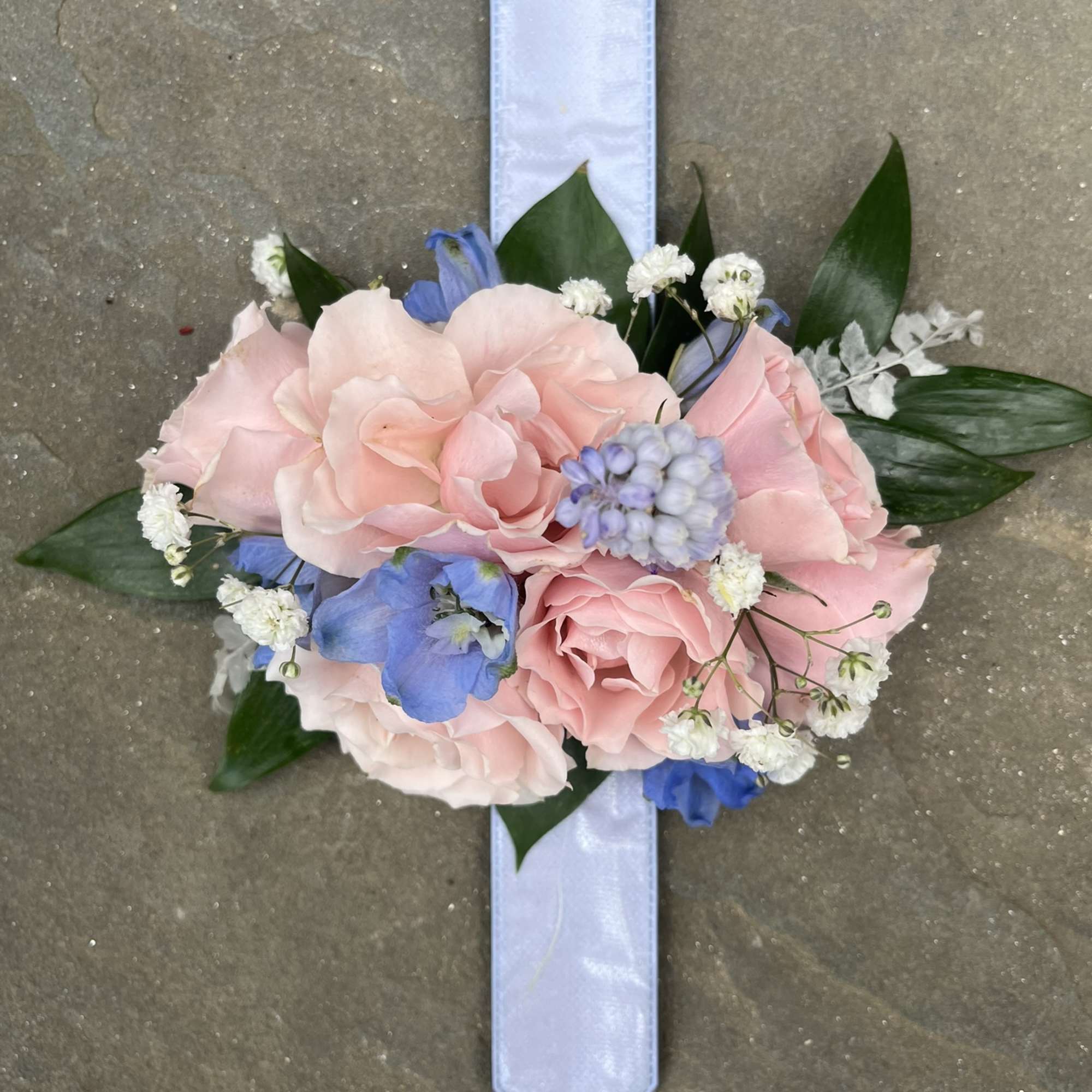 A small arrangement of beautiful flowers and greens secured to a snap
