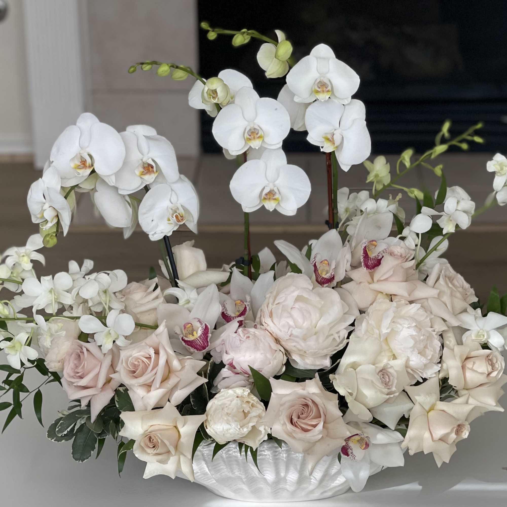 White orchids and pale roses arranged in a low white bowl