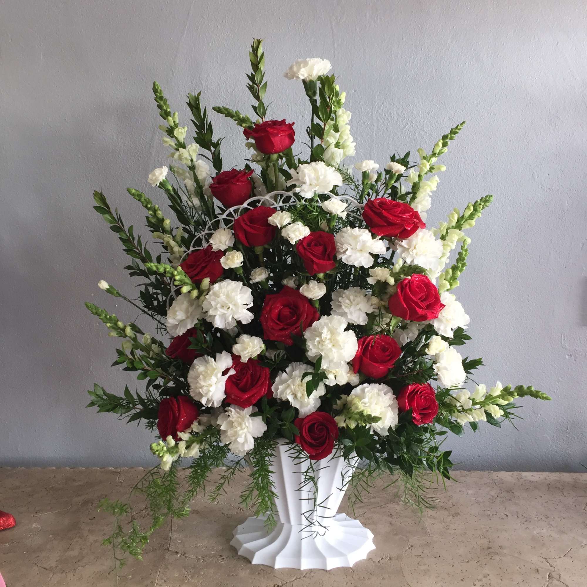 Red roses and white carnations in a tall white vase