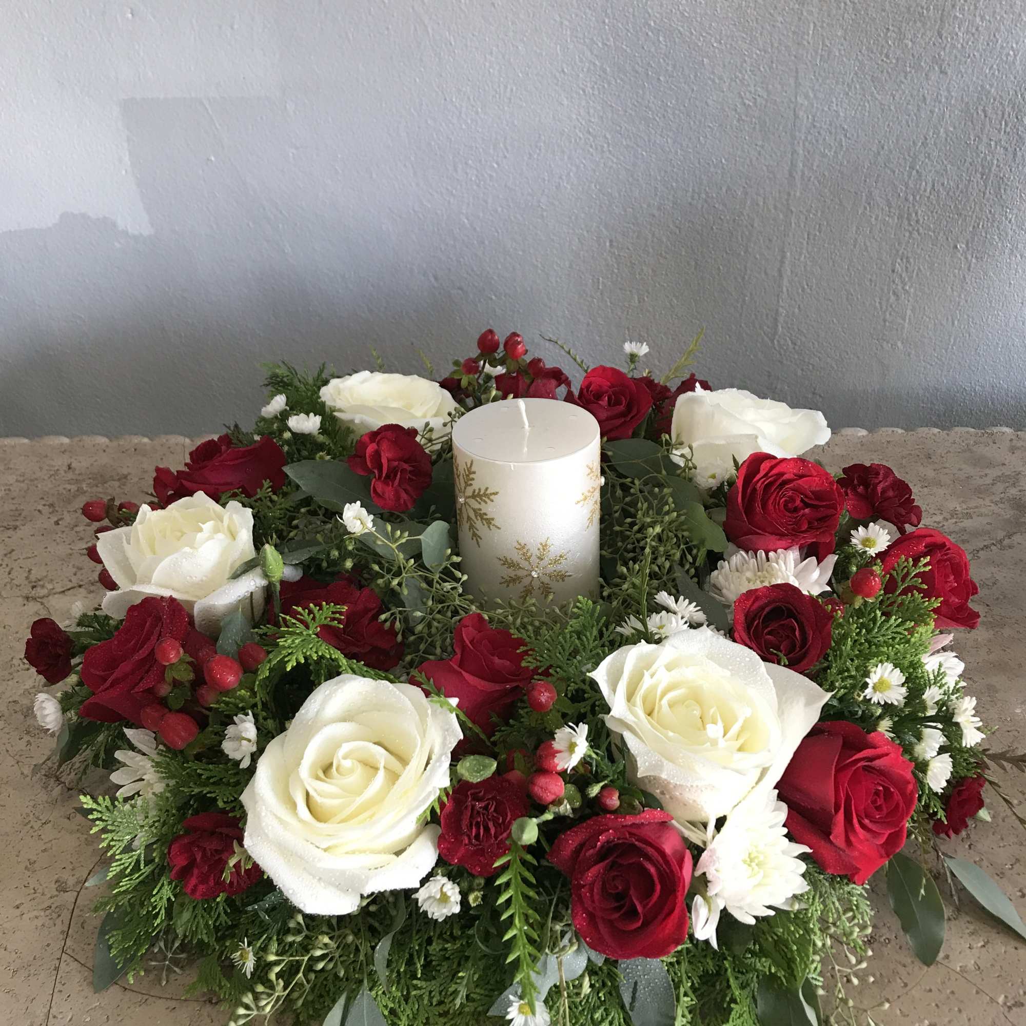 Red and white rose centerpiece with a white candle in the middle