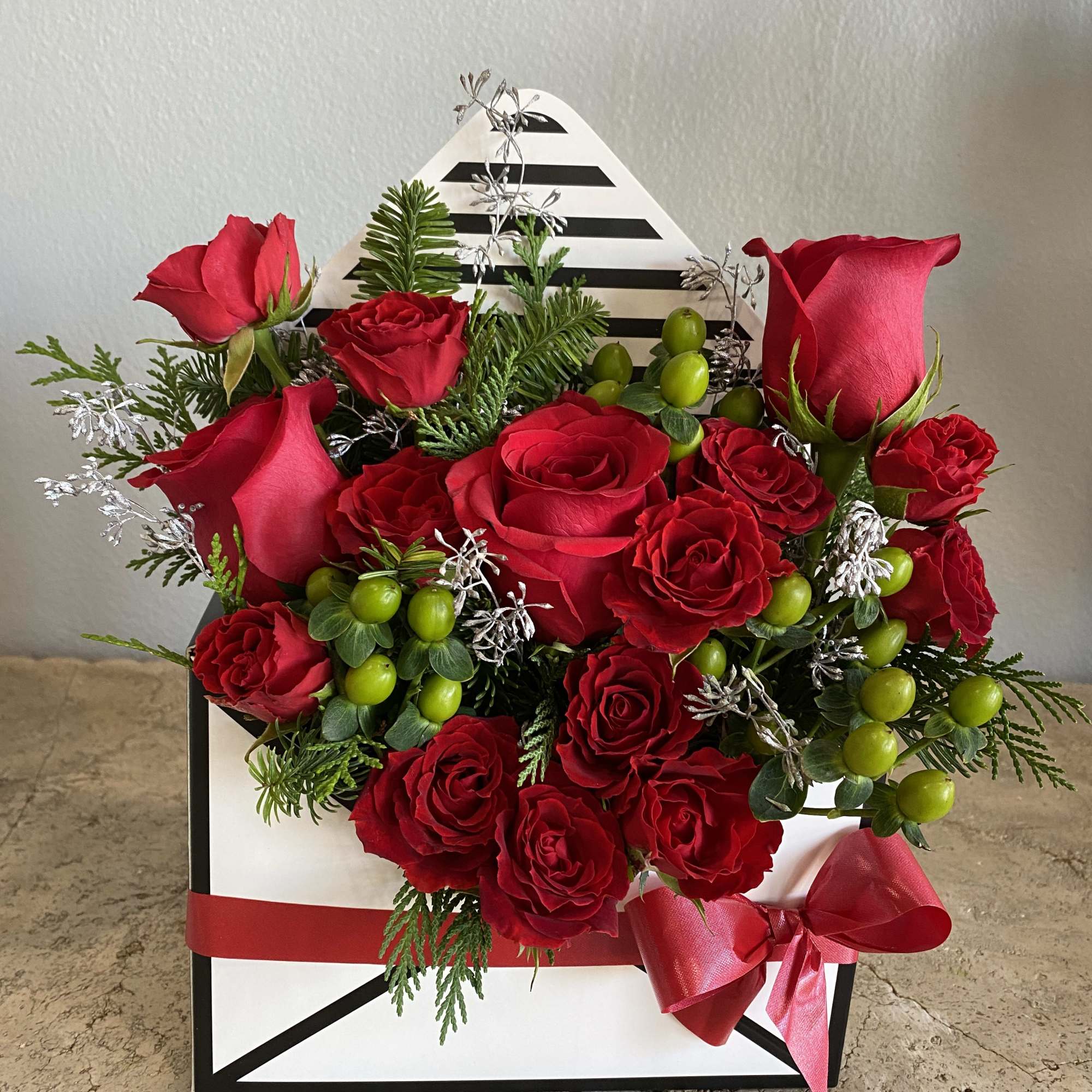 Red roses arranged in a black-and-white gift box with a red ribbon