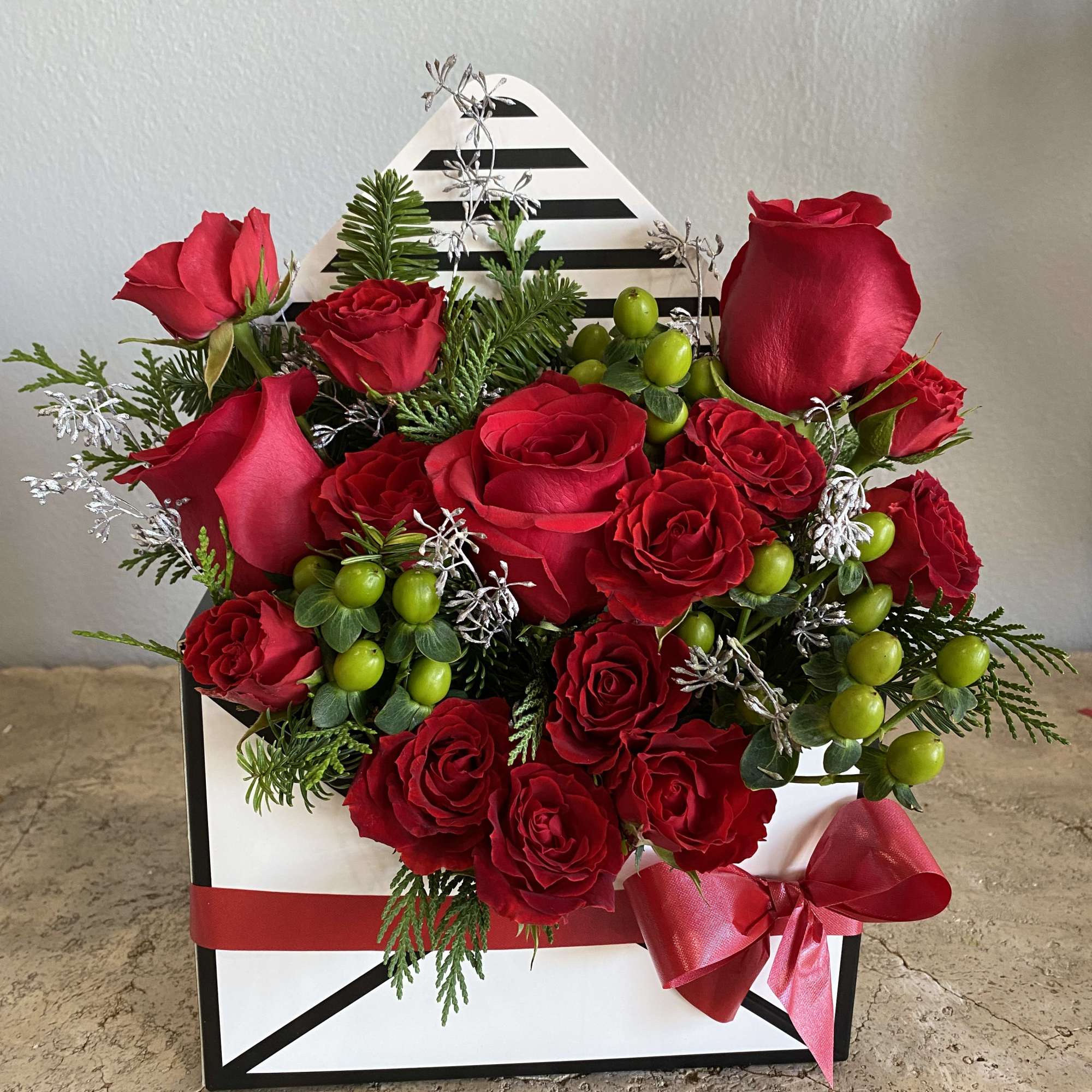 Red roses arranged in a striped gift box with a red ribbon