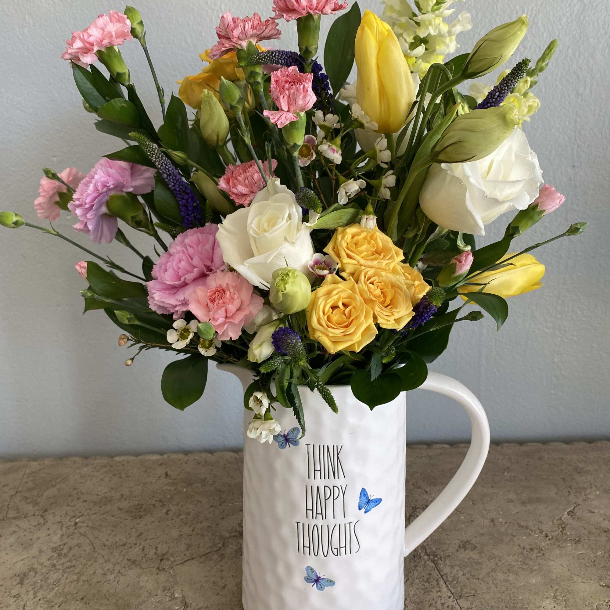 Mixed bouquet in a white mug with pink, yellow, and white flowers