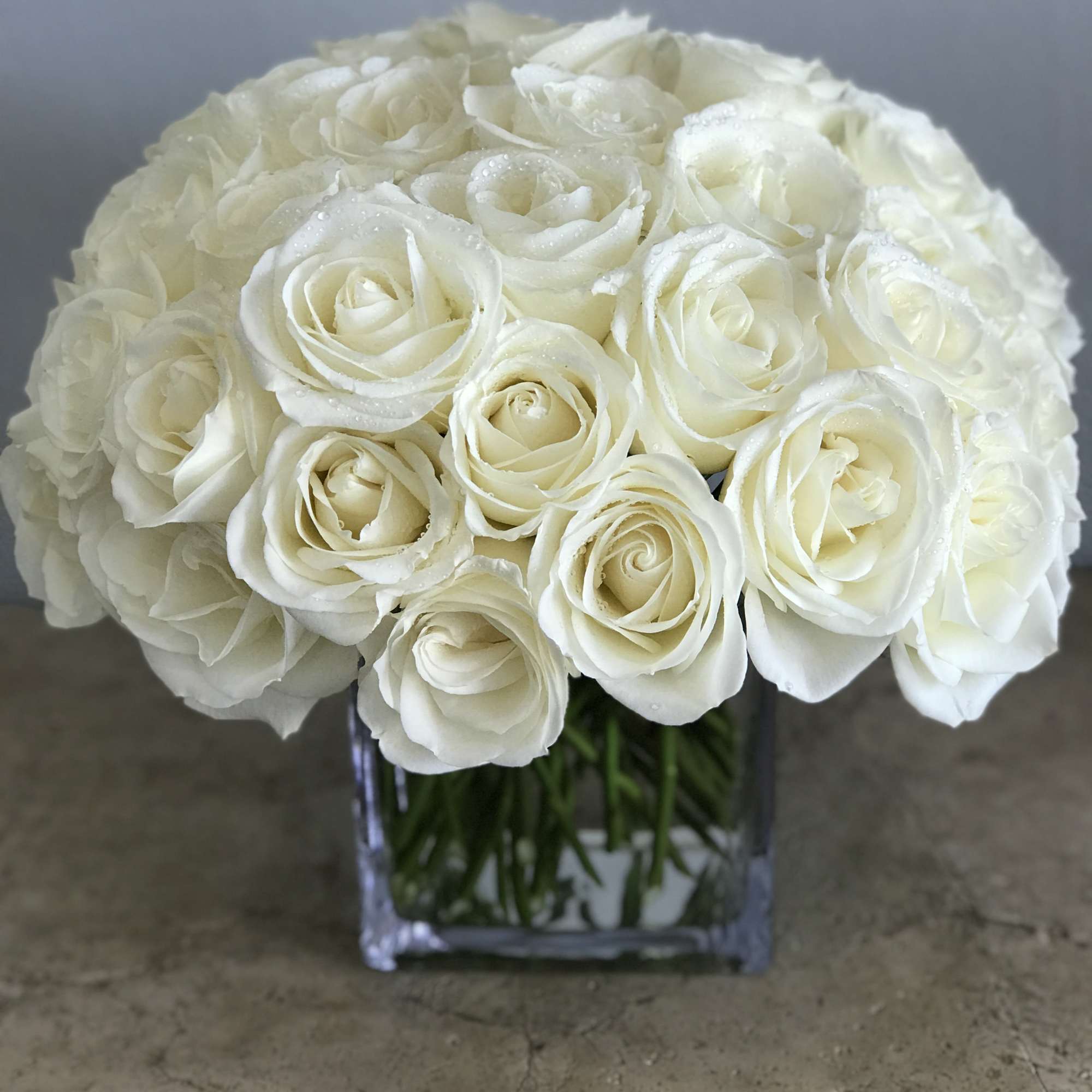 White rose bouquet in a clear square vase