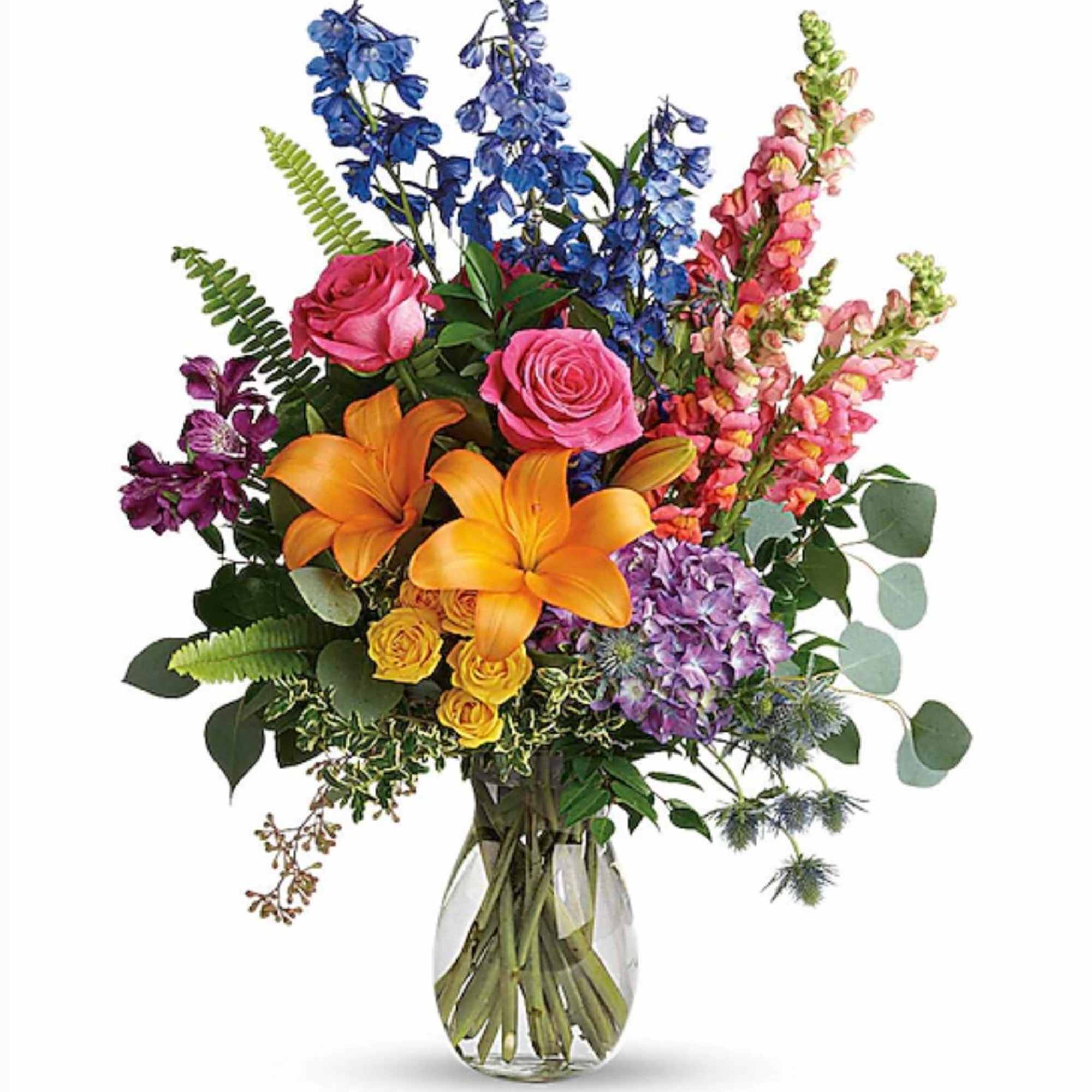 Tall mixed bouquet with orange lilies, pink roses, blue delphinium and purple hydrangea in a clear glass vase