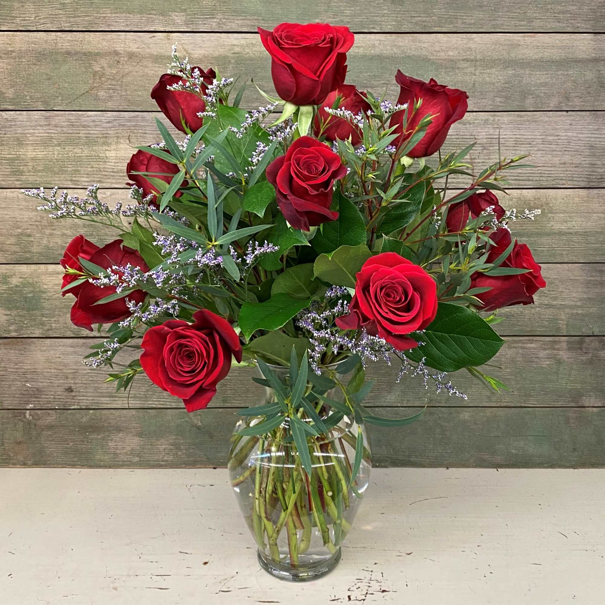 Red roses arranged in a clear glass vase with airy filler flowers
