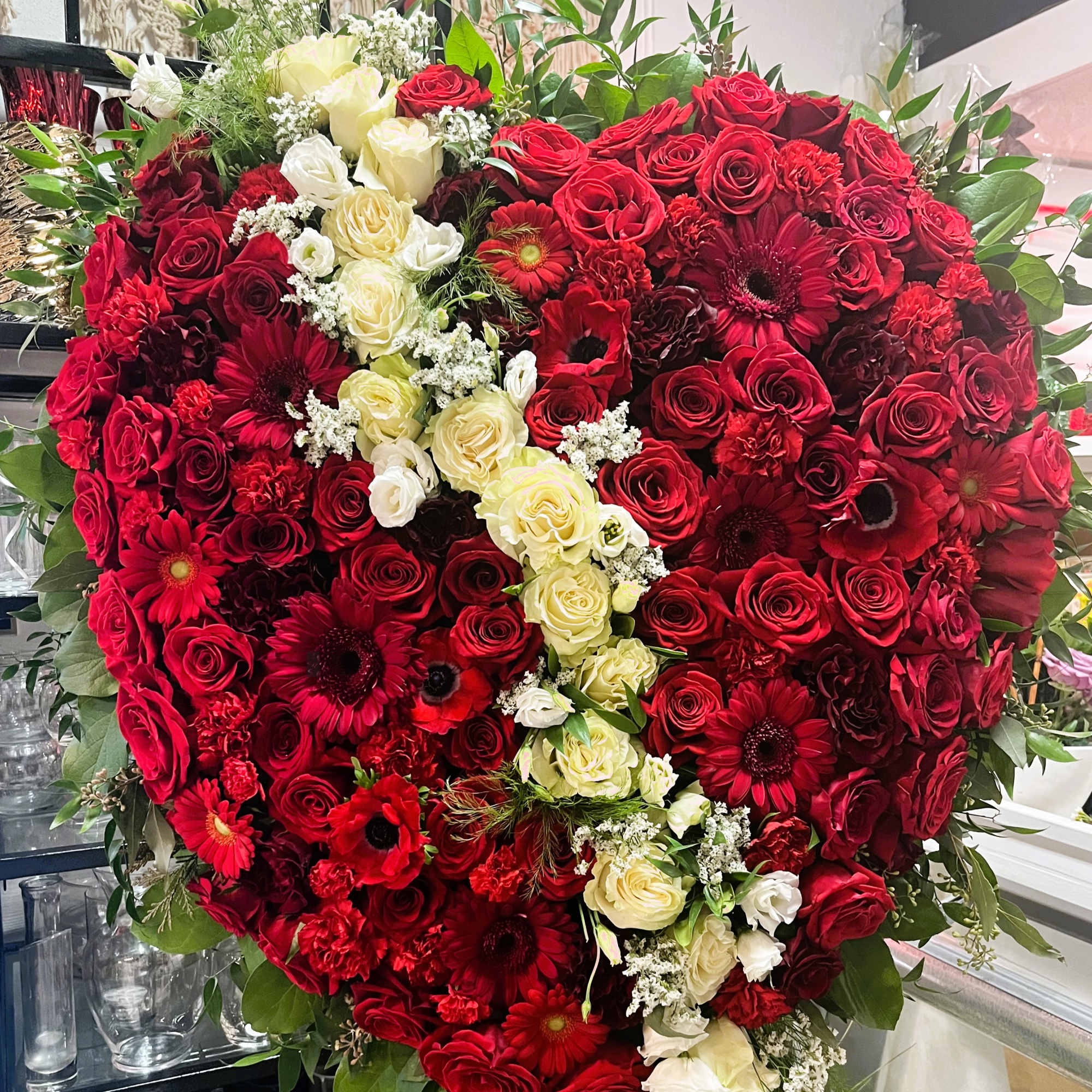 Heart-shaped bouquet of red and white roses with red daisies