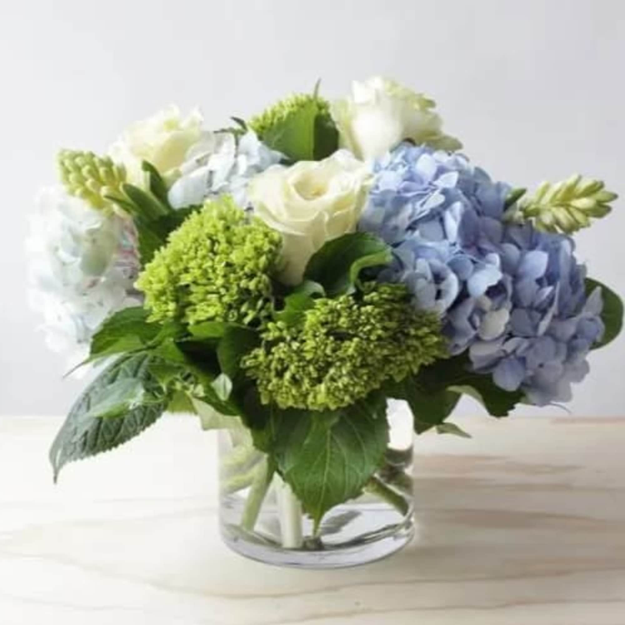 Blue and white hydrangea bouquet in a clear glass vase, photo 3 of 3