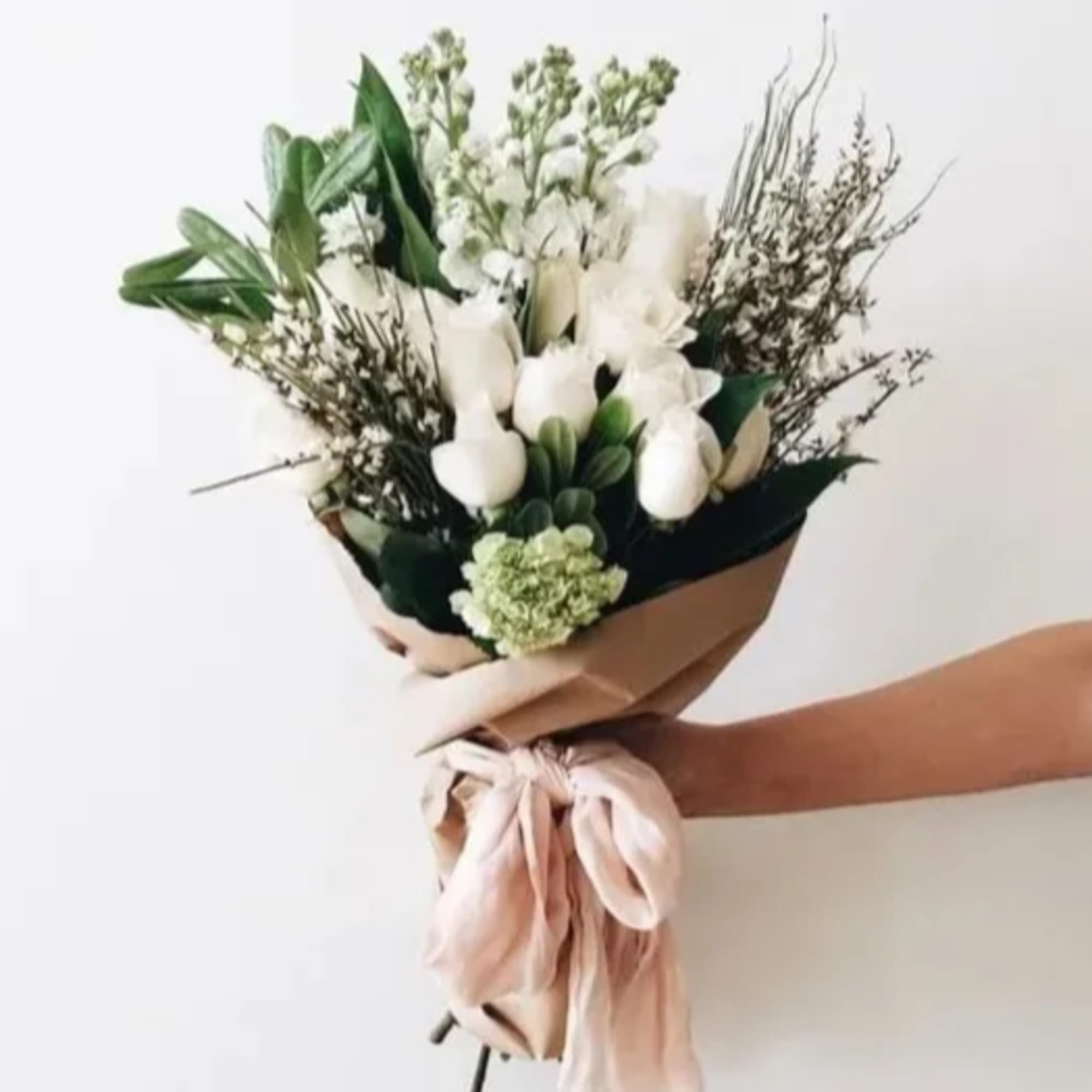 White bouquet with mixed greenery and a blush ribbon wrap