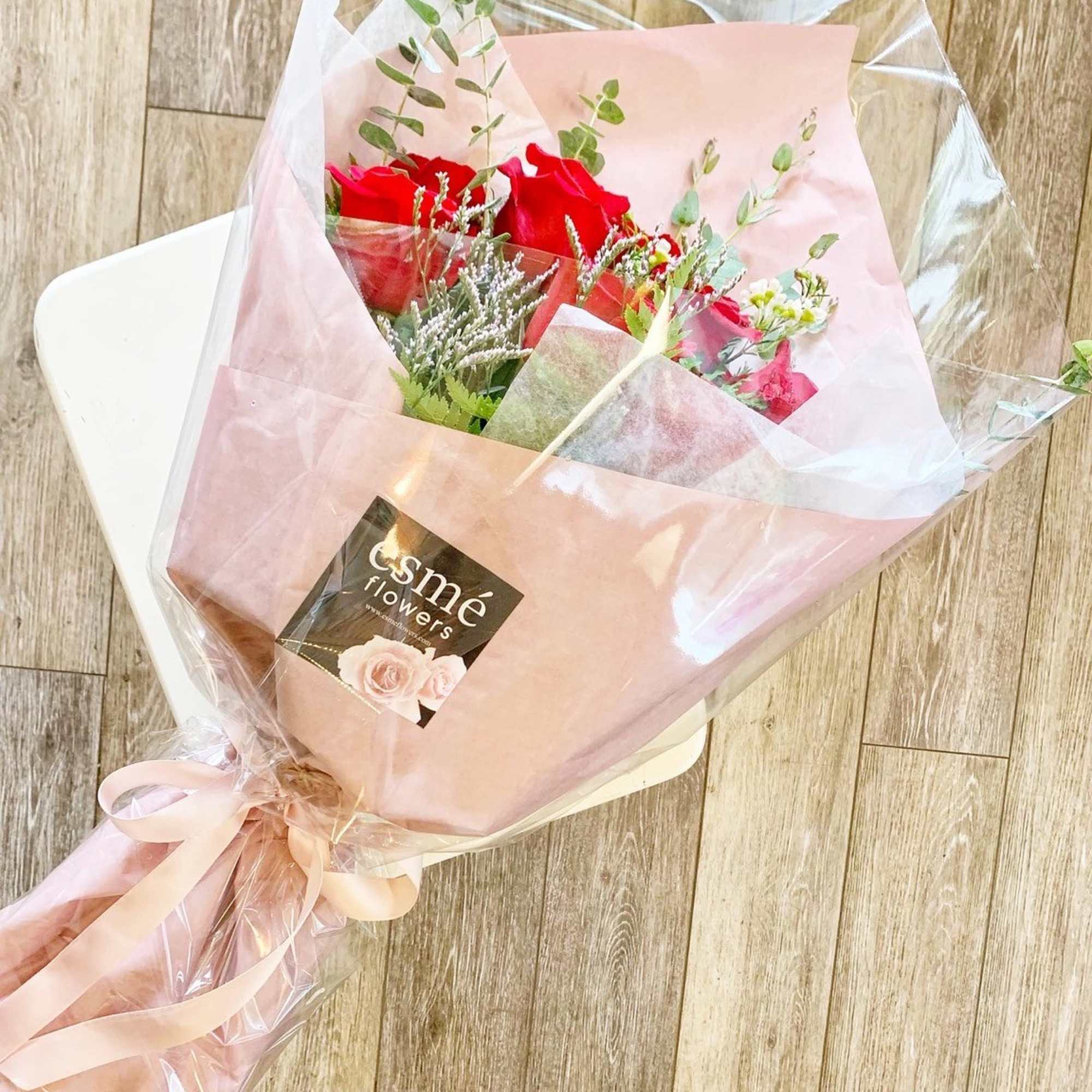 Wrapped bouquet of red roses with pink paper and ribbon