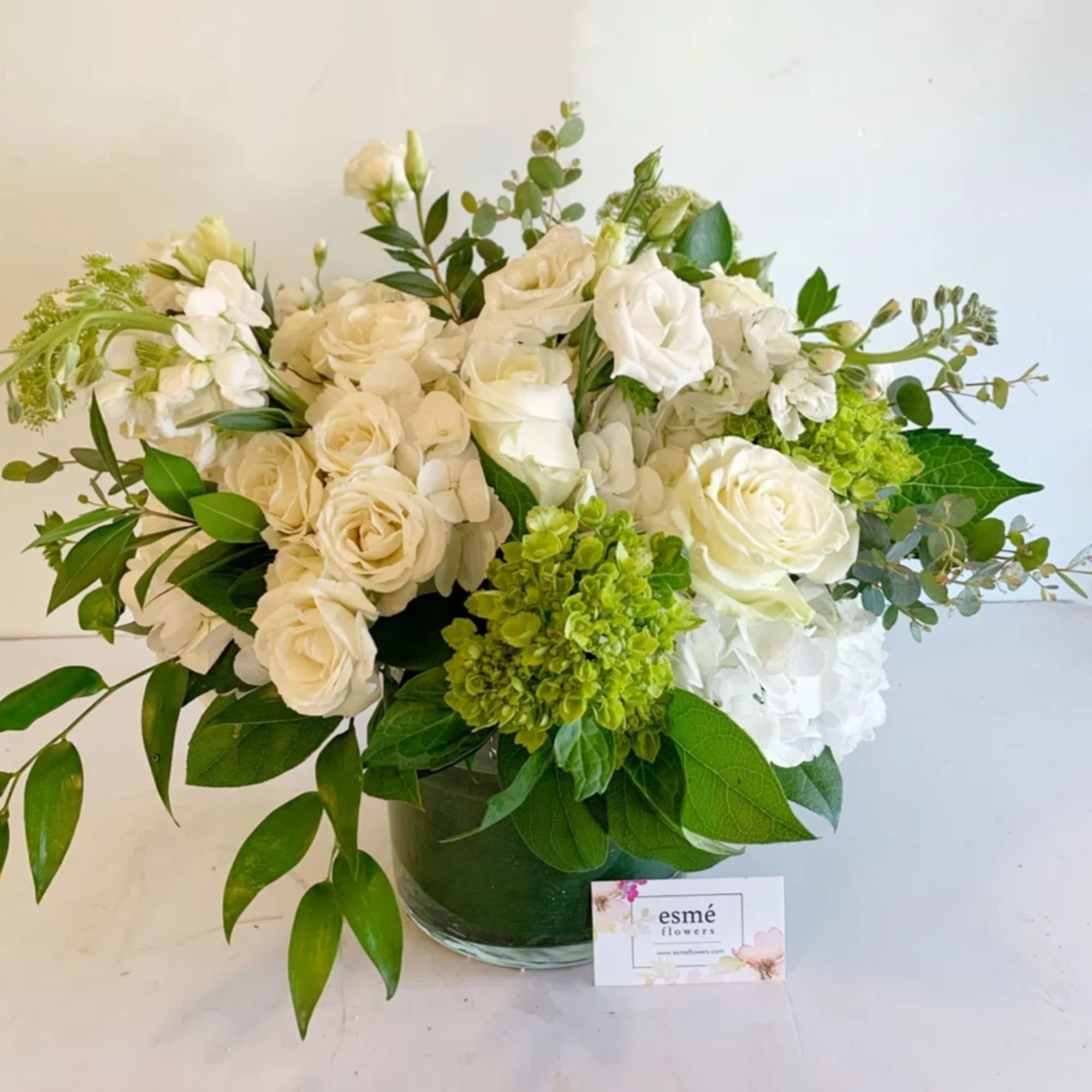 White rose bouquet with green hydrangeas in a glass vase