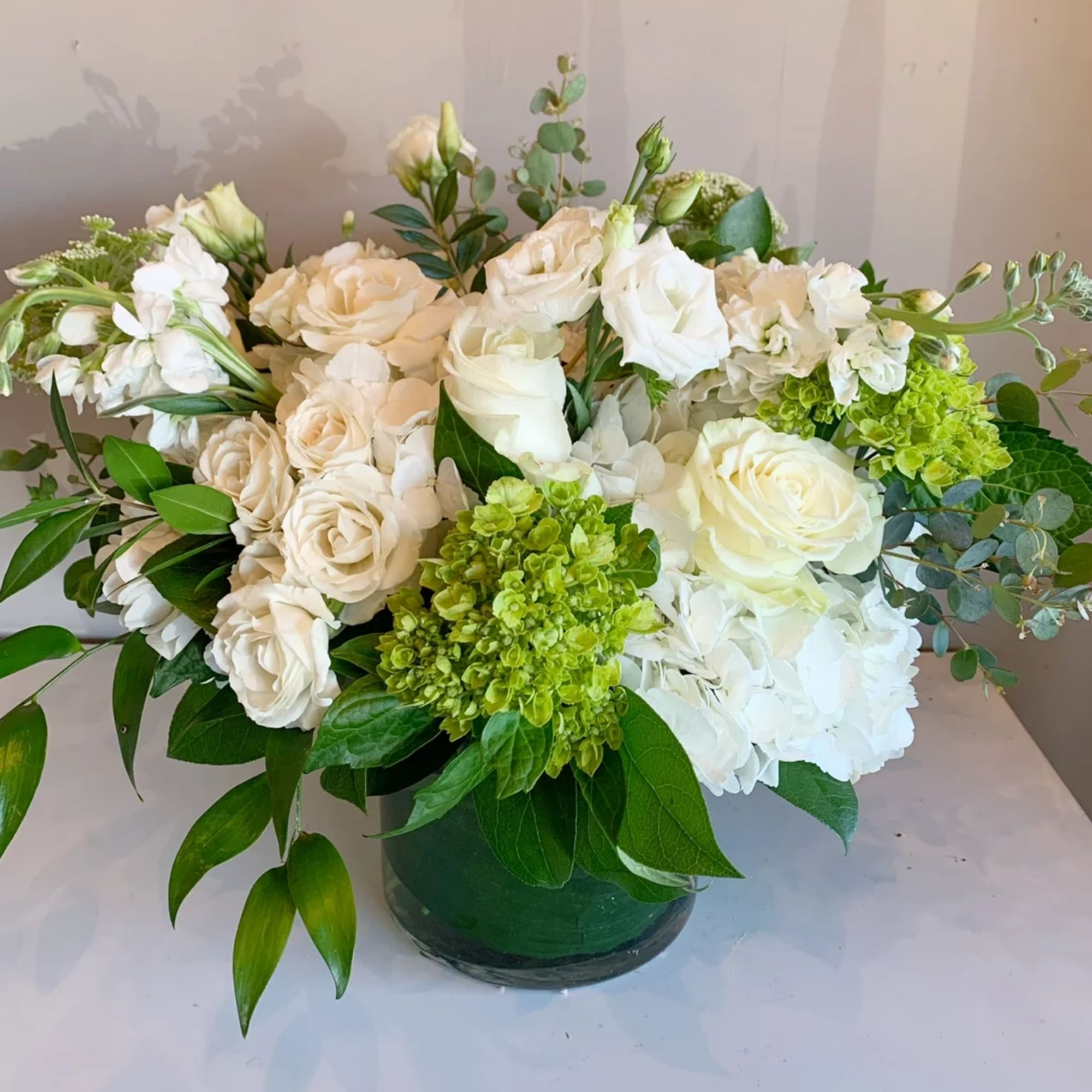 White and cream roses with green hydrangea in a low vase arrangement