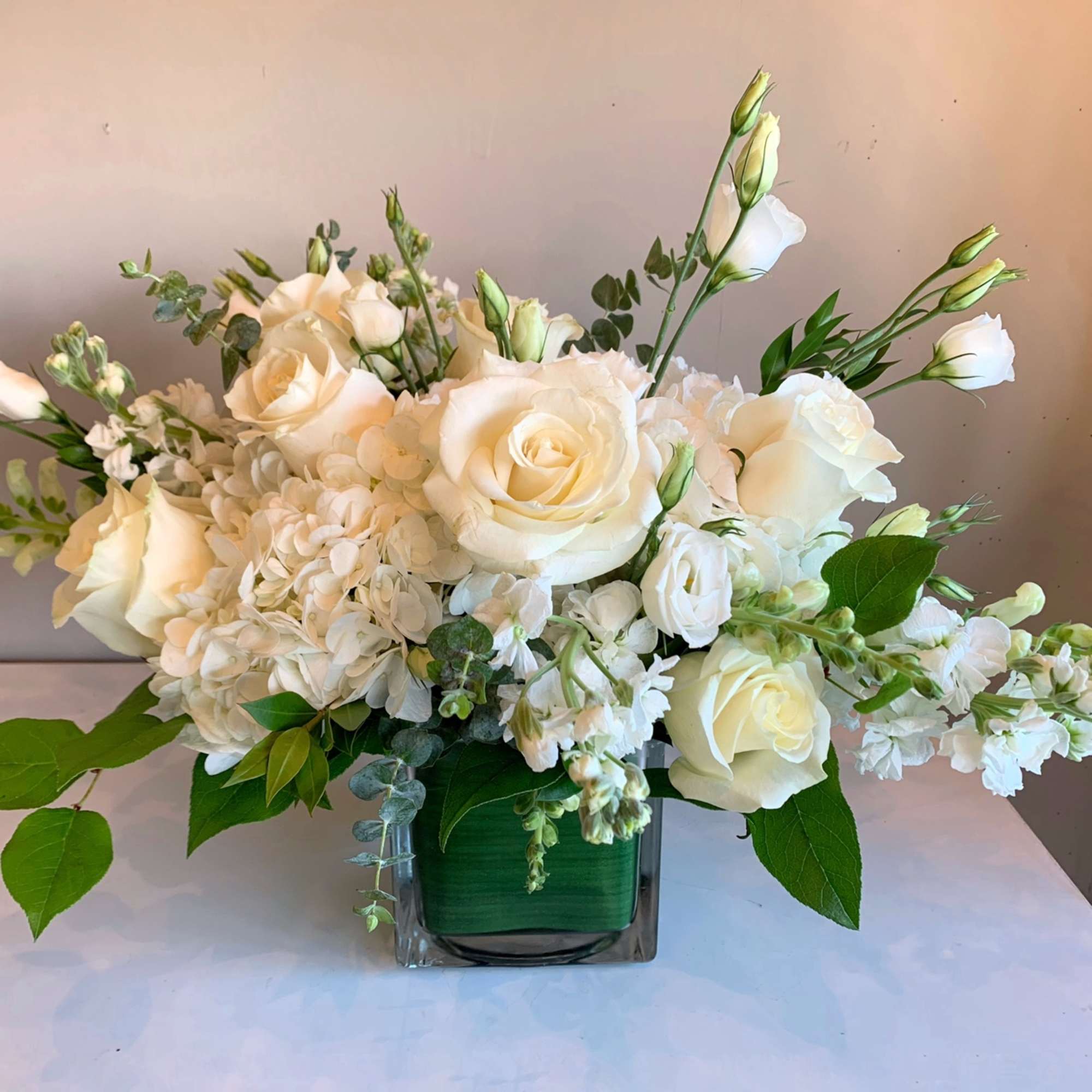 White rose and hydrangea arrangement in a square glass vase