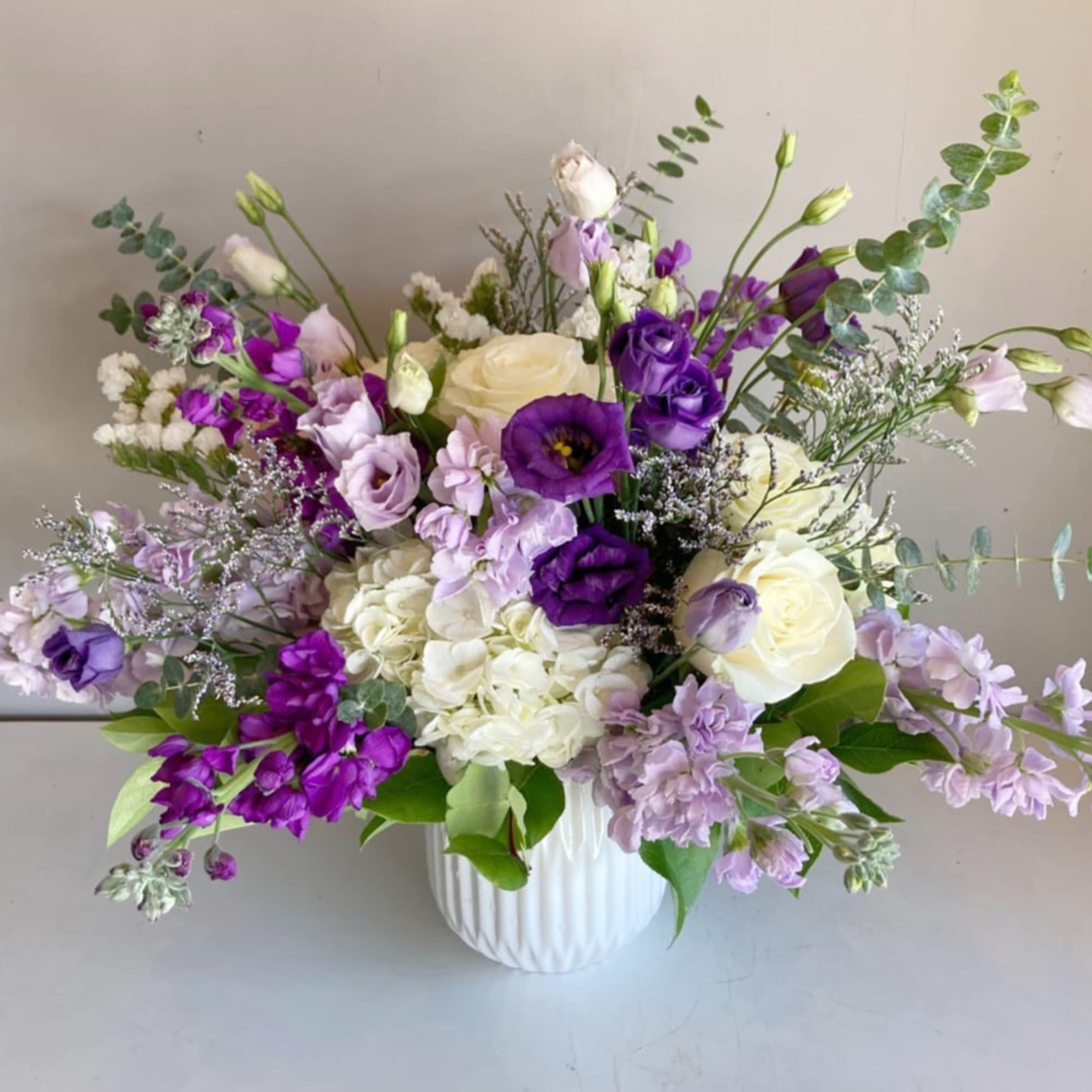 Purple and white mixed bouquet in a white vase