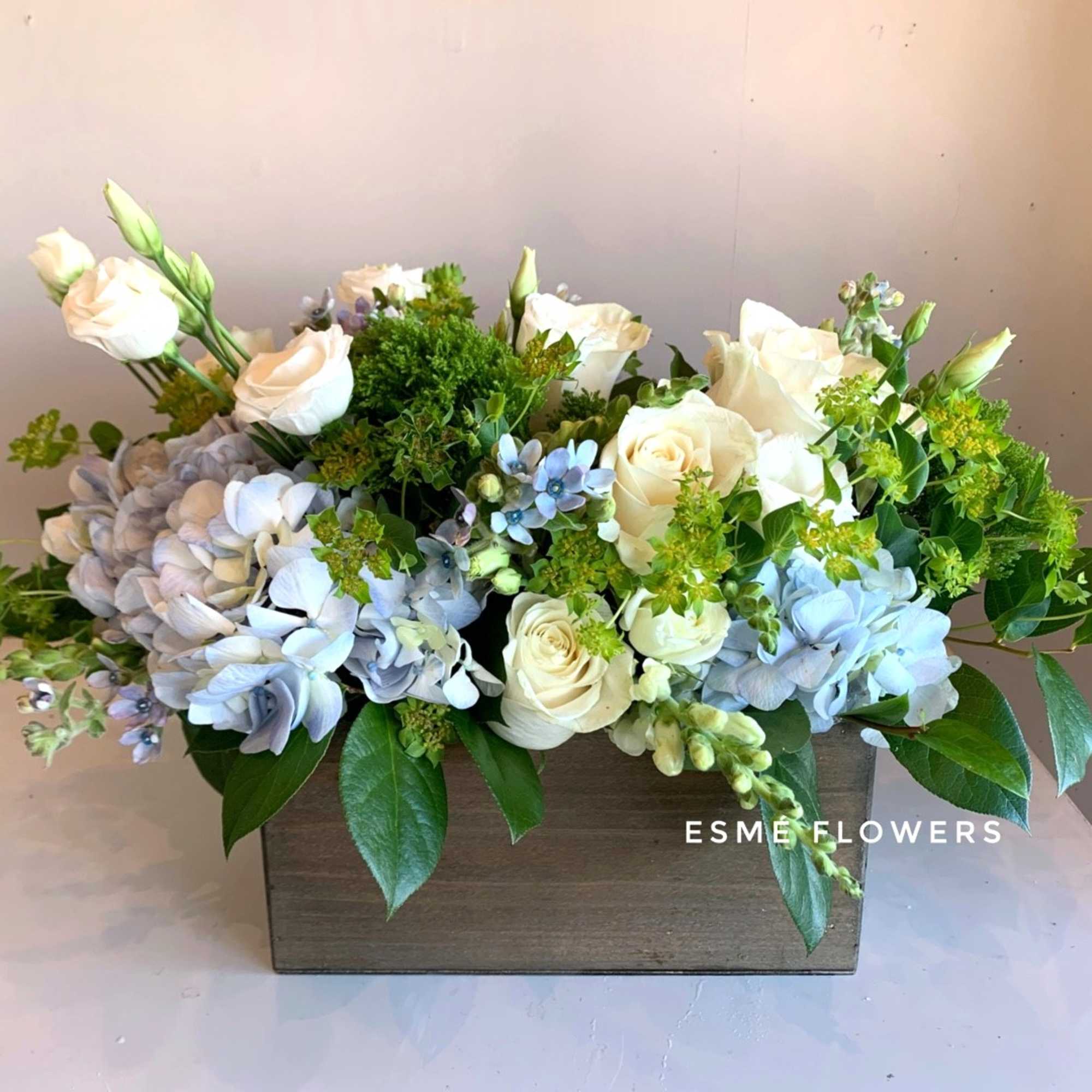 White roses and blue hydrangeas in a rectangular wooden box