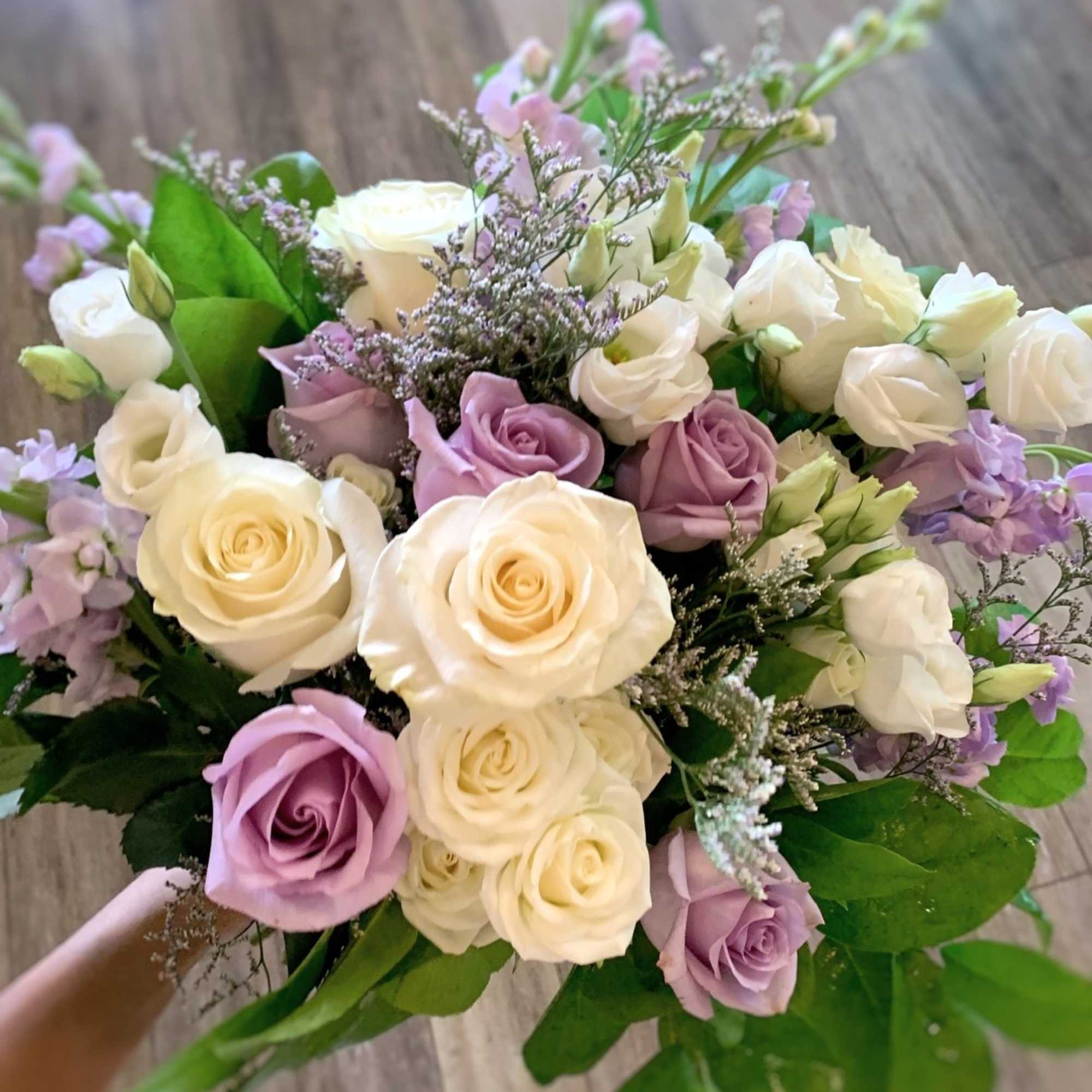 Bouquet of cream and lavender roses with purple filler flowers