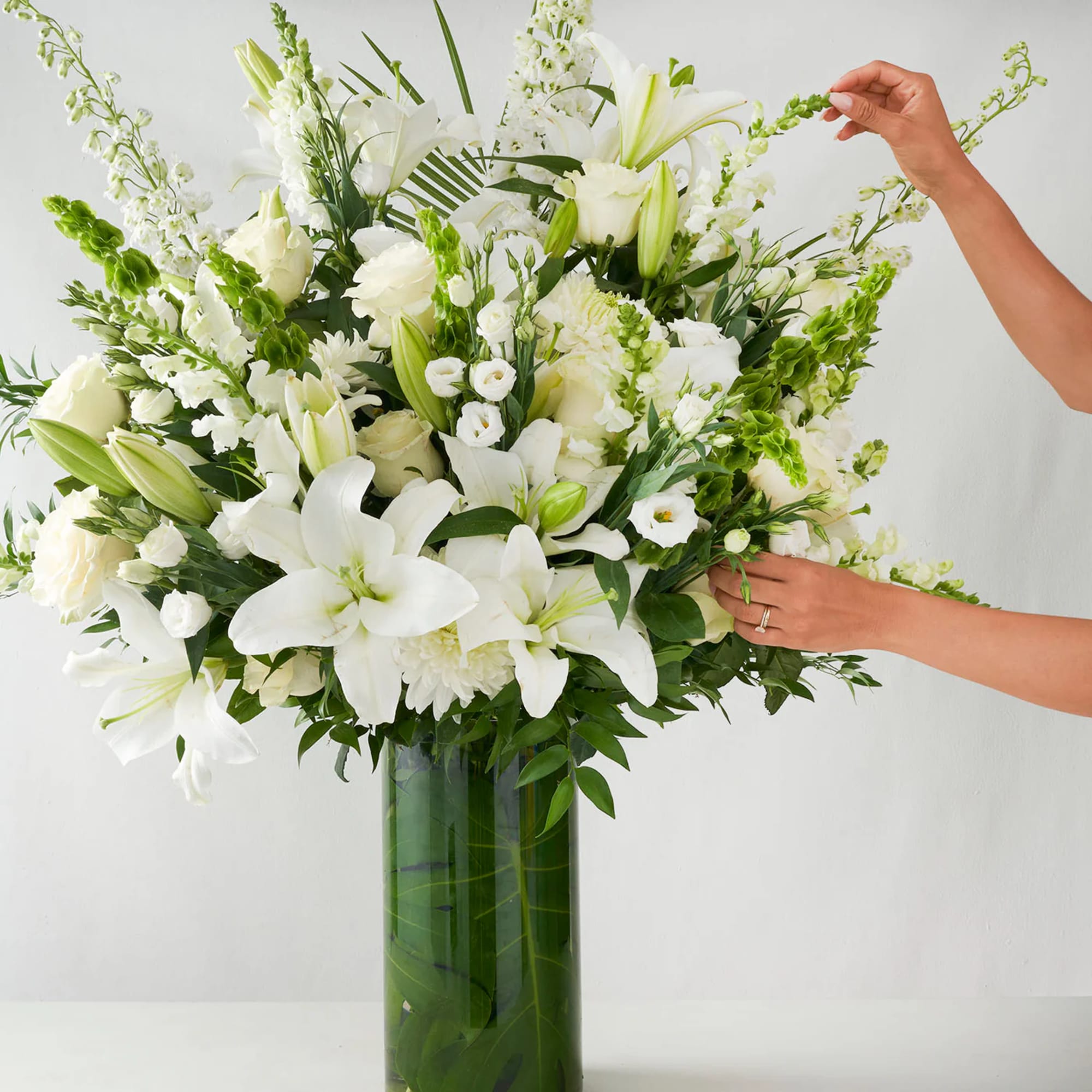 Large white floral arrangement in a tall glass vase
