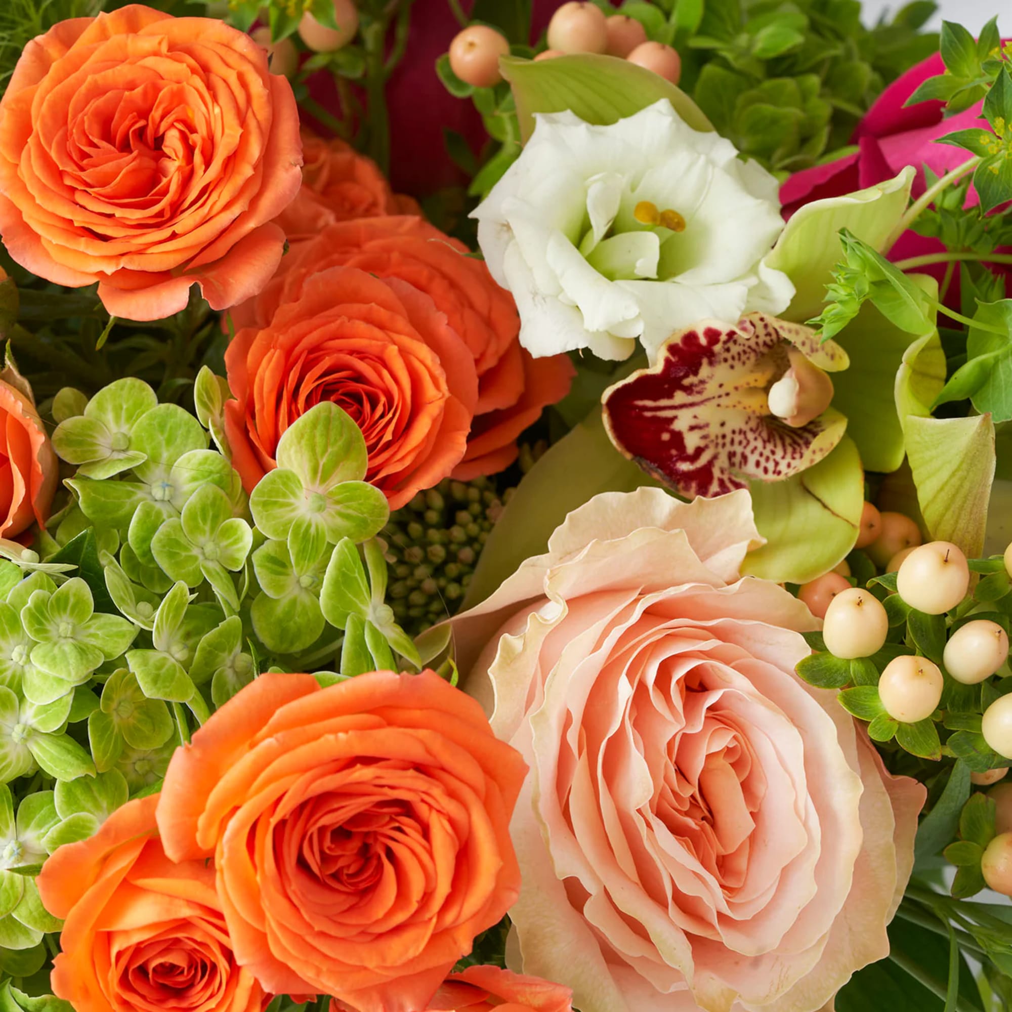 Close-up bouquet with orange and blush roses, white lisianthus, and green accents