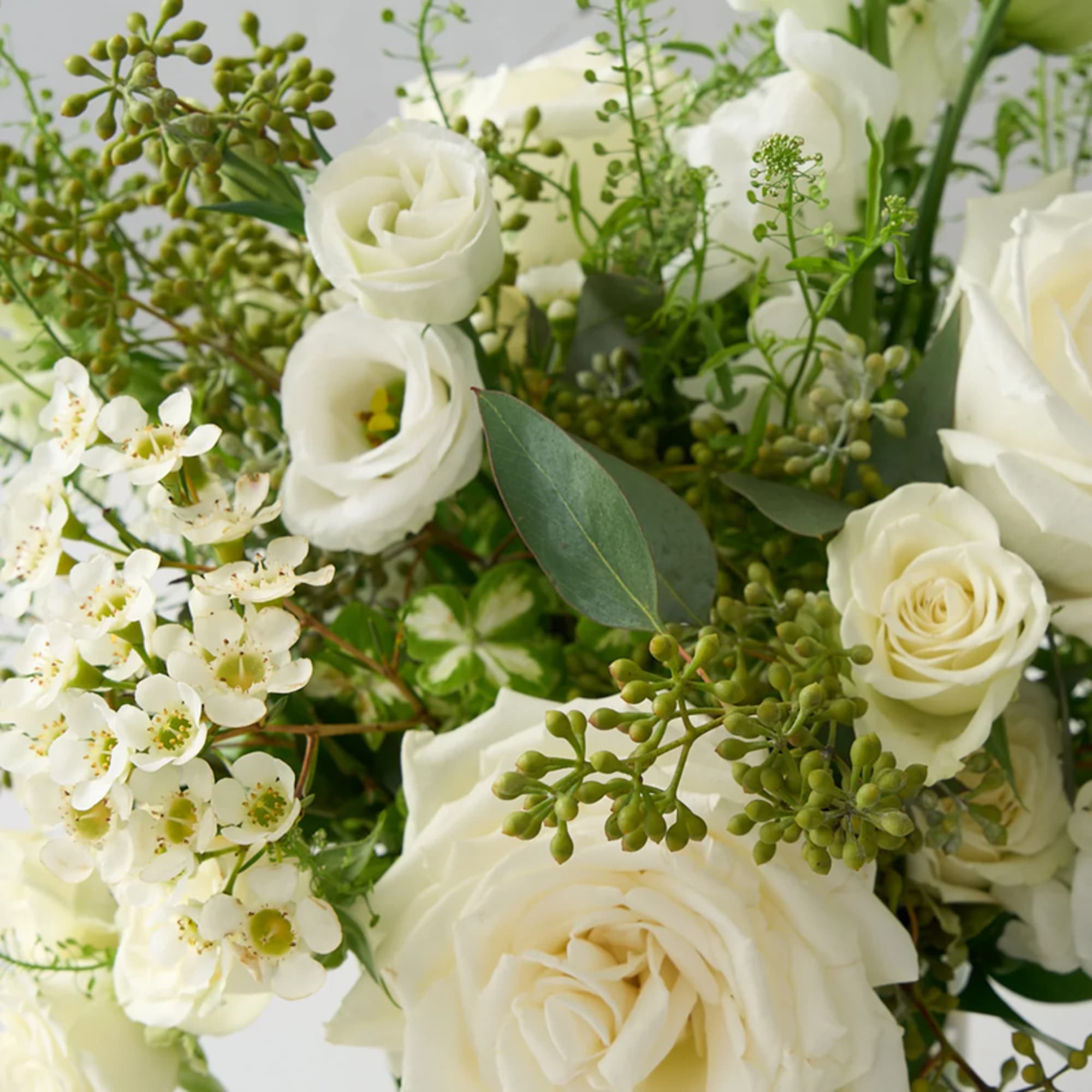 White roses and small white blossoms with green filler in a bouquet