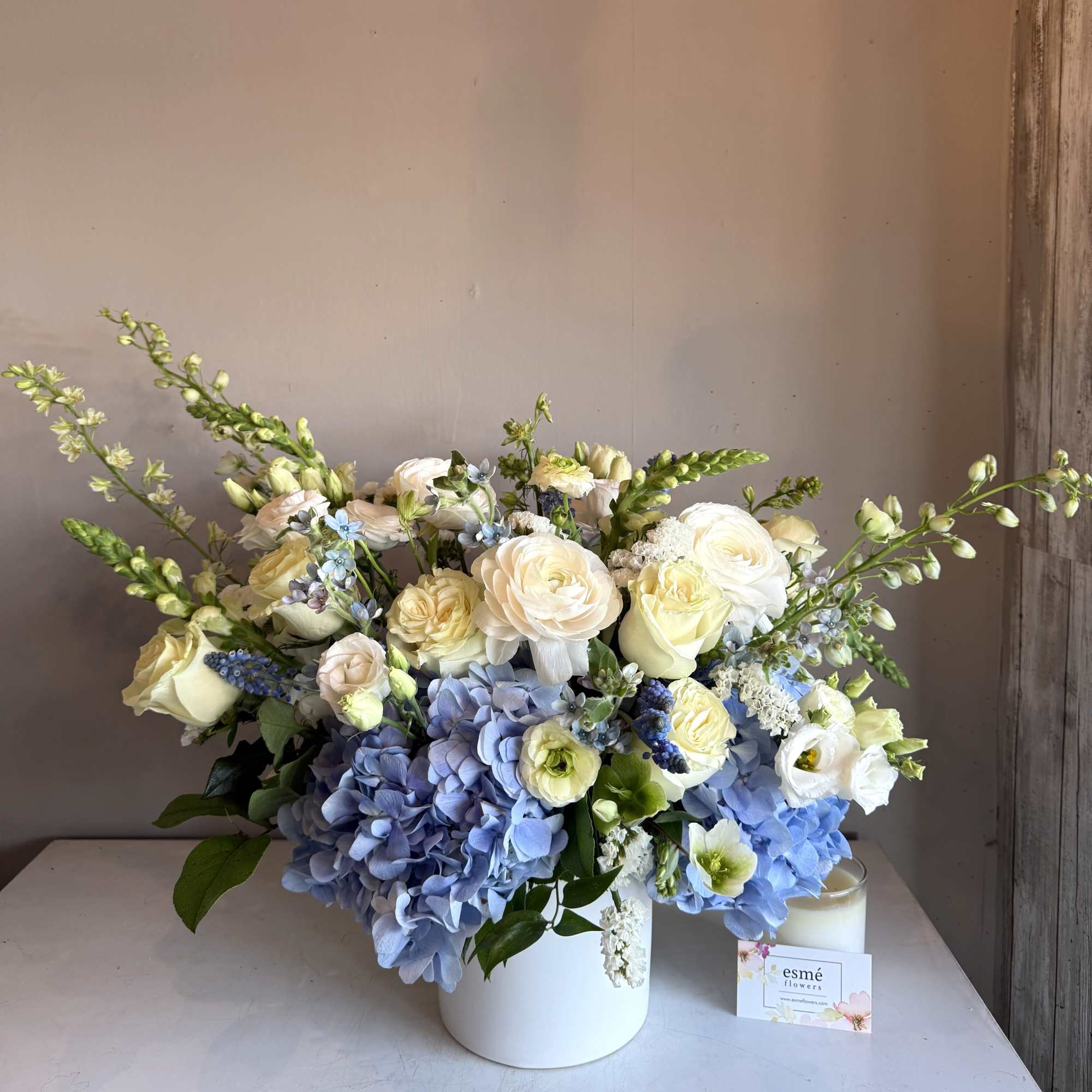 White and blue floral arrangement in a white vase