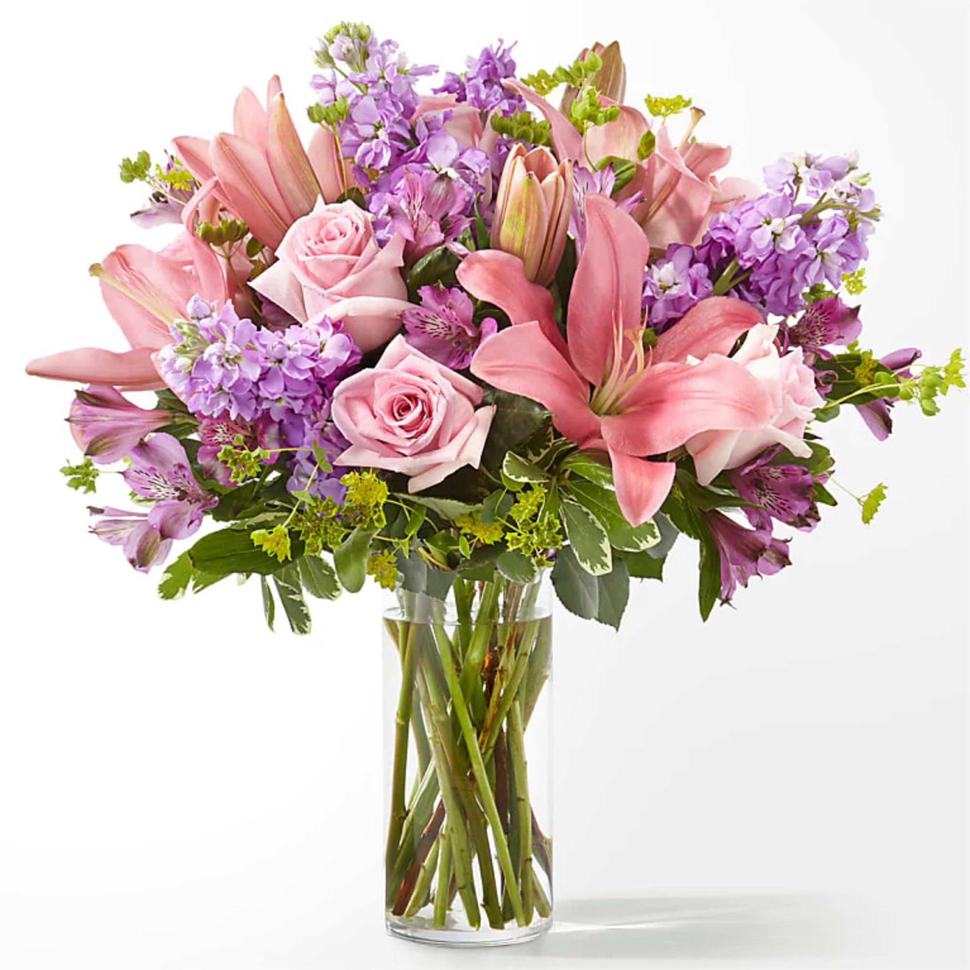 Pink lilies, roses, and purple flowers in a clear glass vase