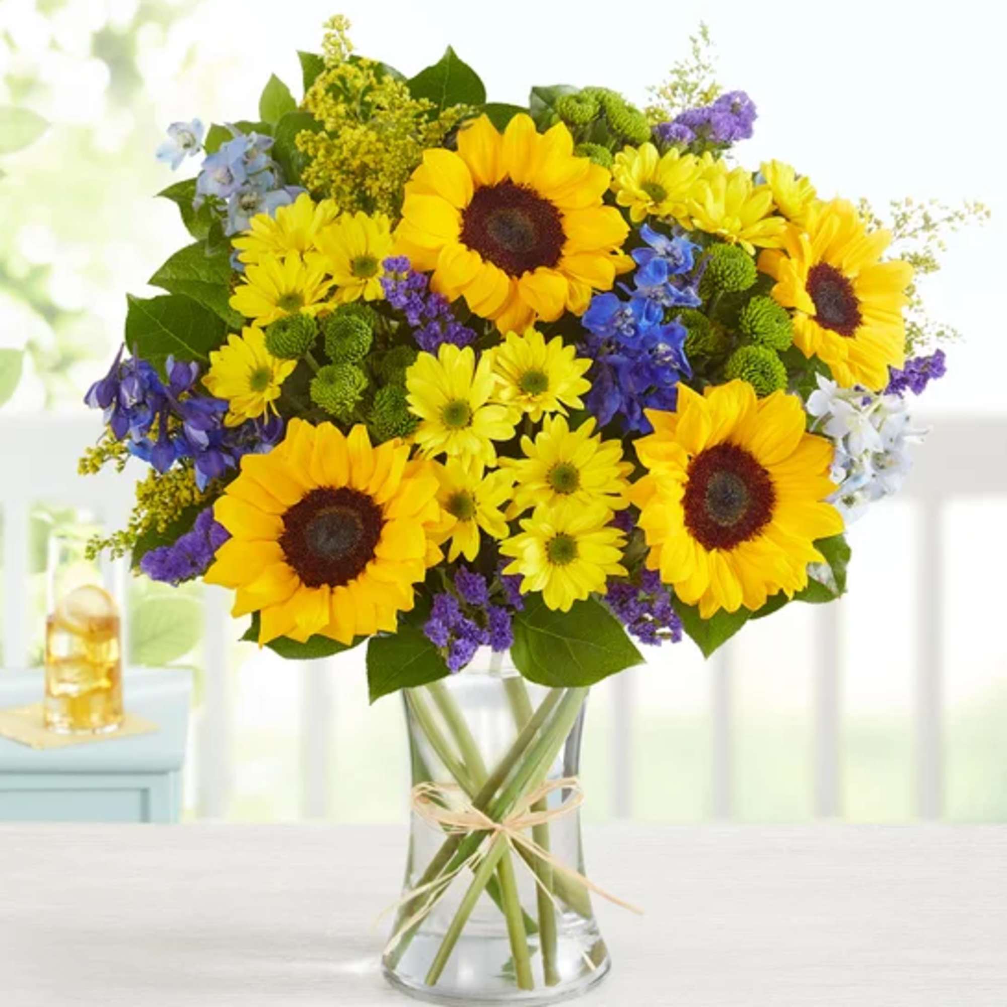 Sunflower bouquet in a clear glass vase with purple and yellow flowers