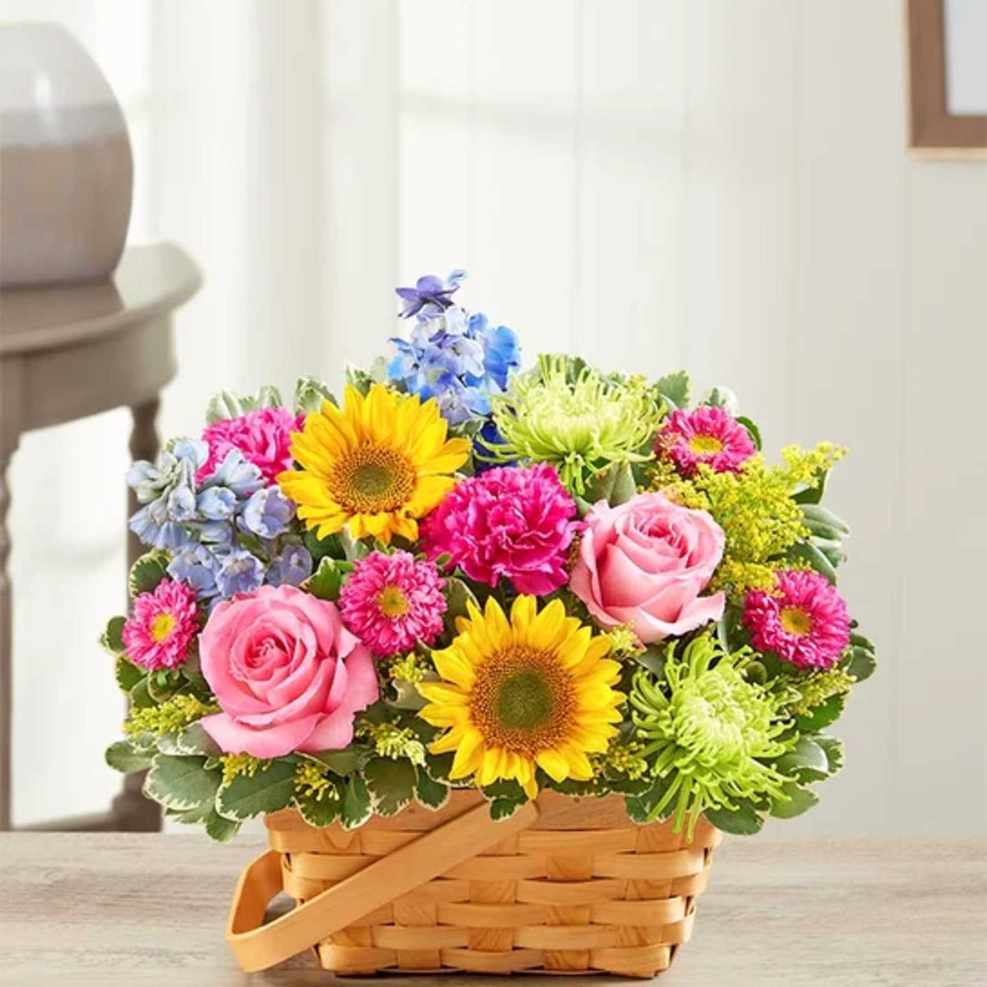 Basket arrangement with pink roses, sunflowers, and colorful mixed blooms