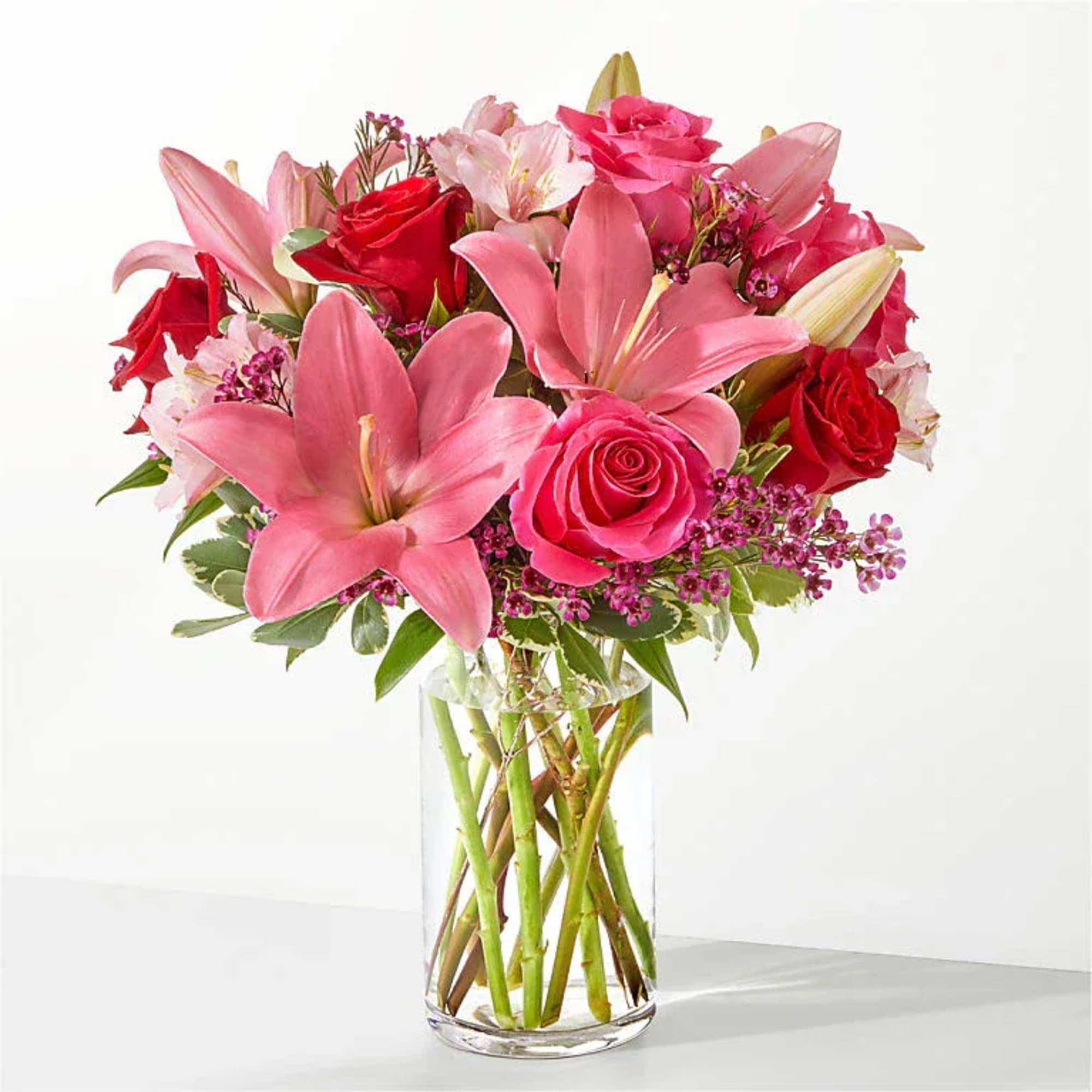 Pink lilies and red roses in a clear glass vase