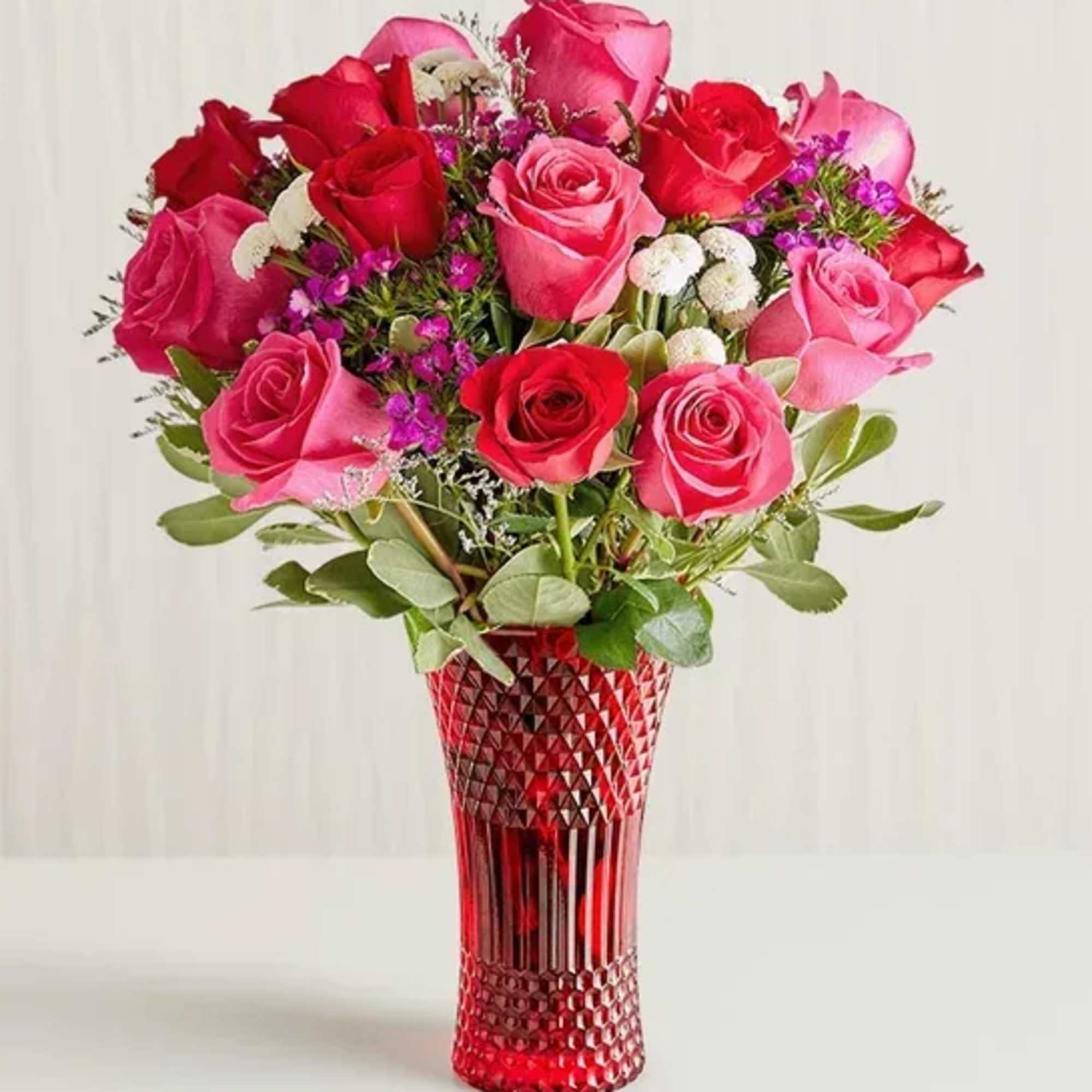 Bouquet of red and pink roses in a red glass vase