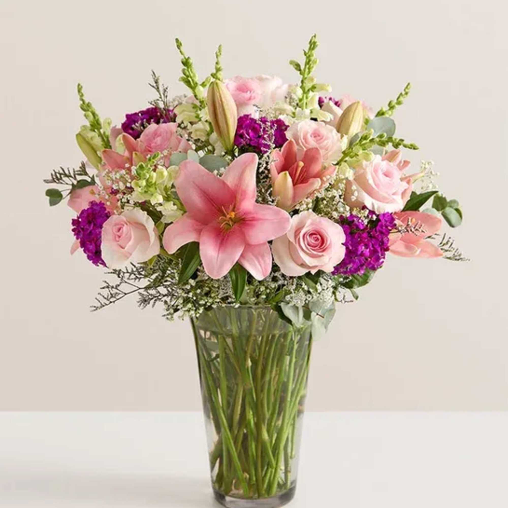 Pink lilies and roses arranged in a clear glass vase