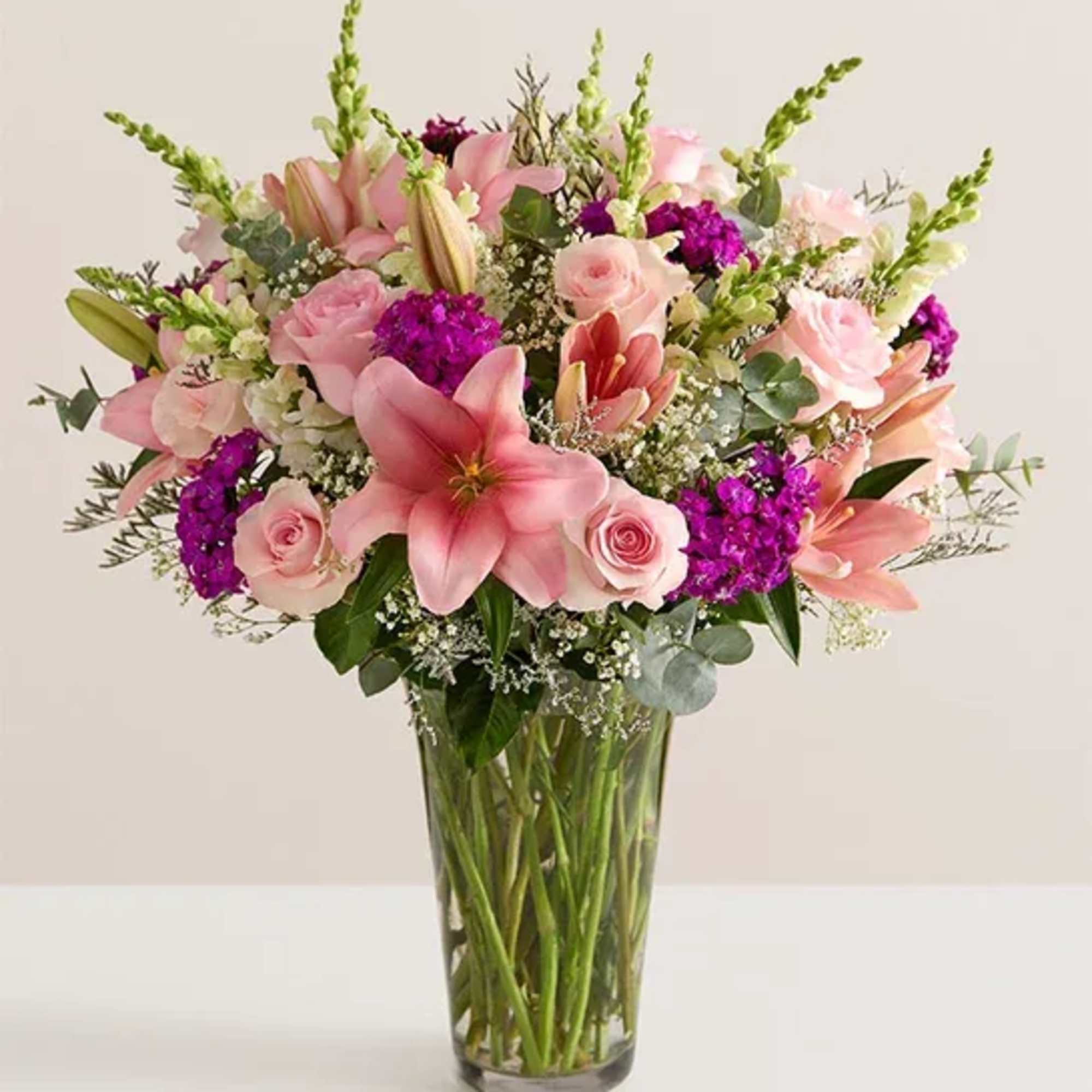 Pink lilies and roses arranged in a clear glass vase