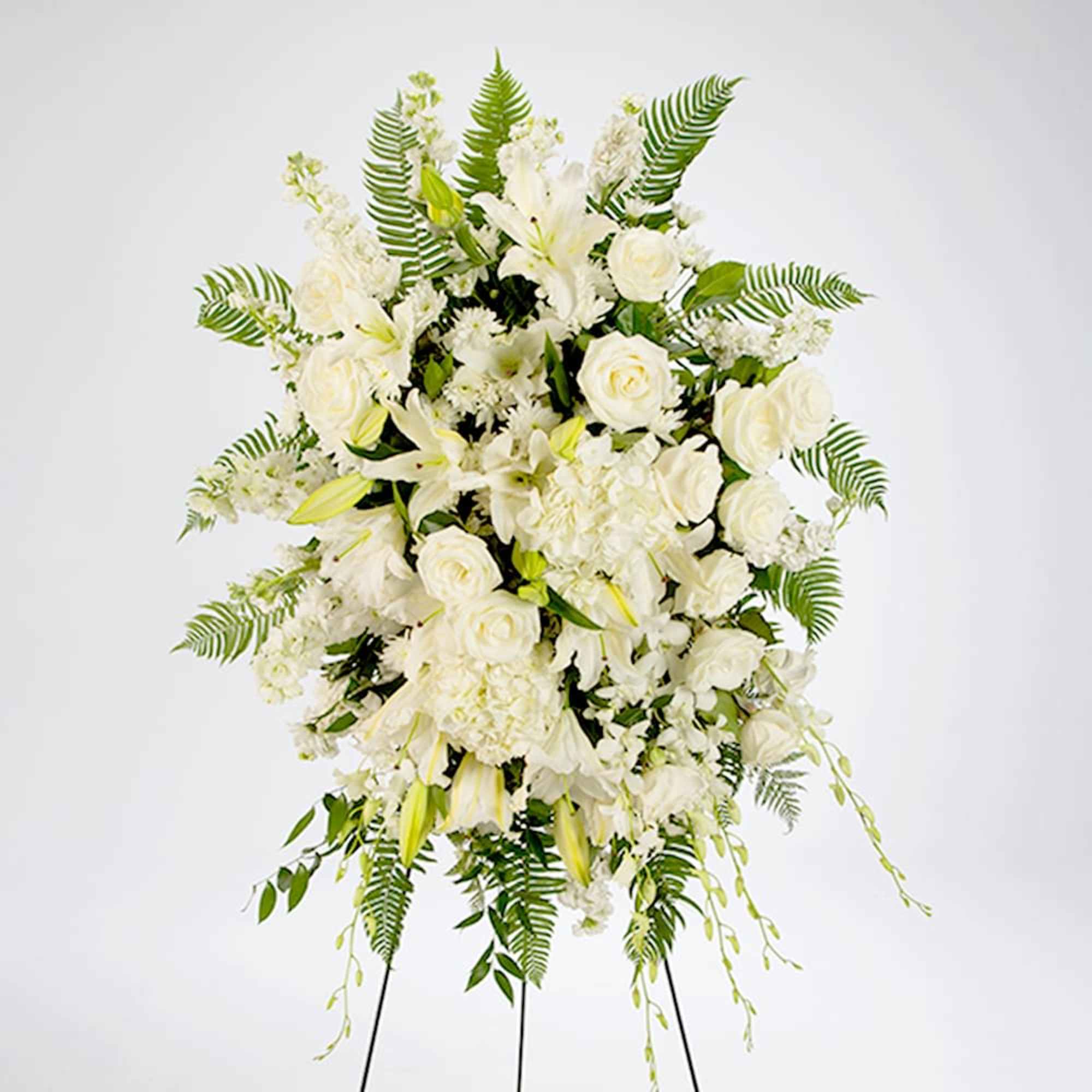 White funeral spray with roses, lilies, and ferns on a stand