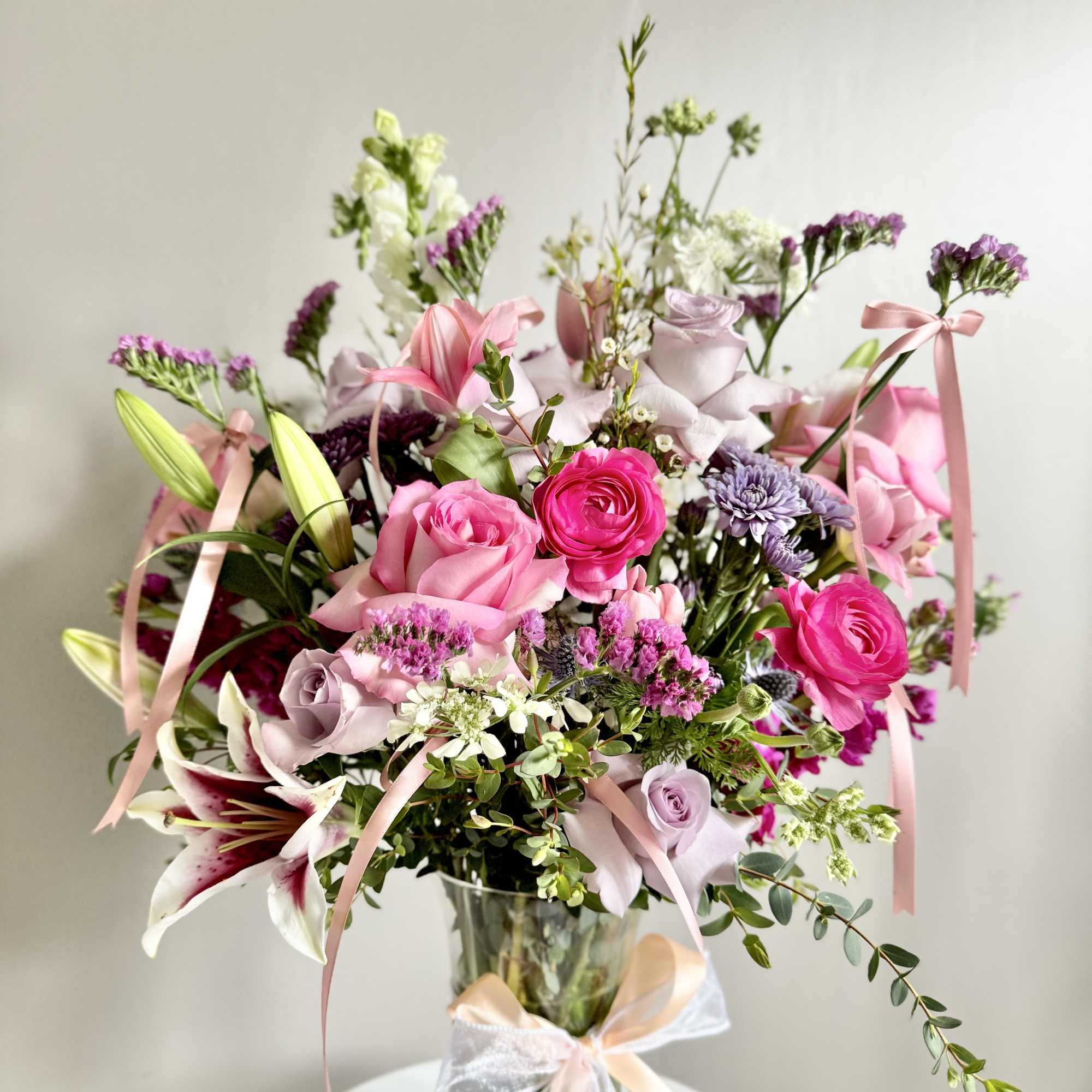 Pink and lavender bouquet in a glass vase with ribbon