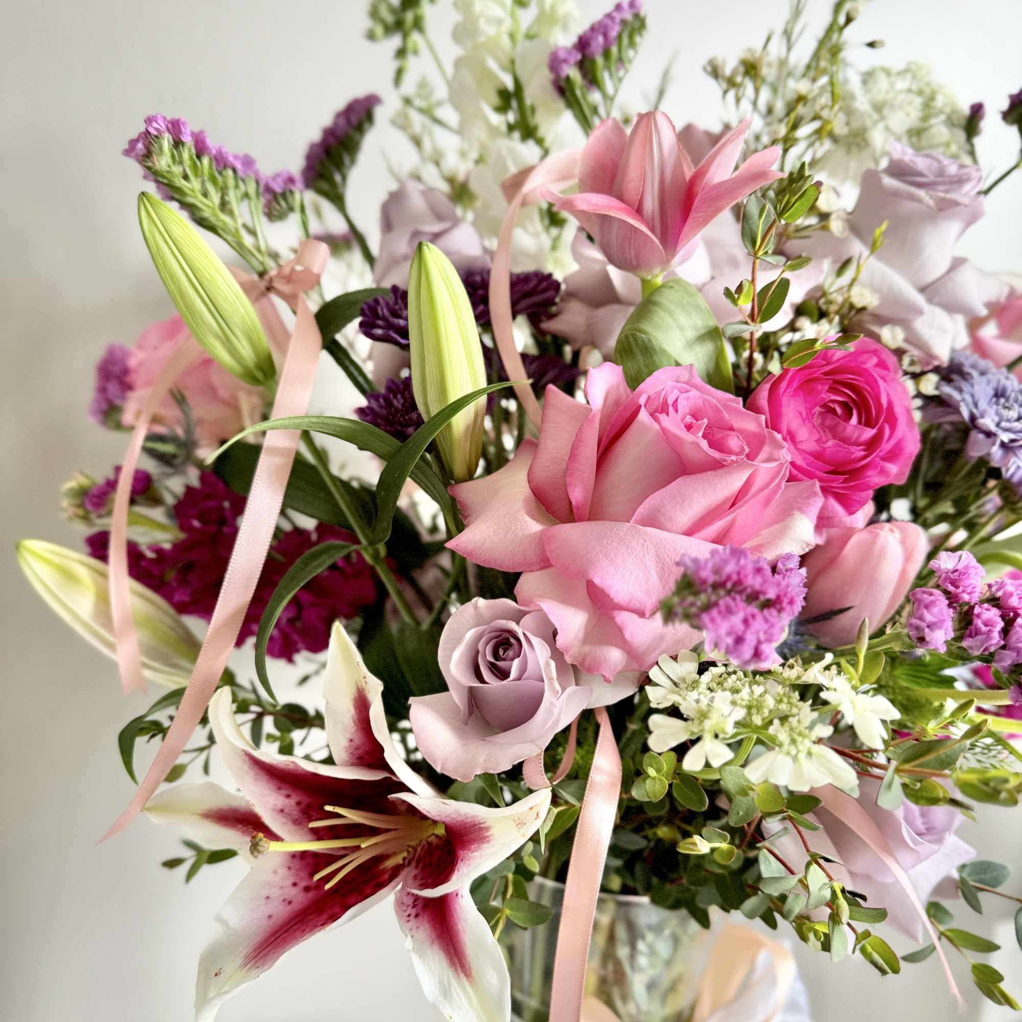 Pink and lavender bouquet with lilies and roses in a glass vase