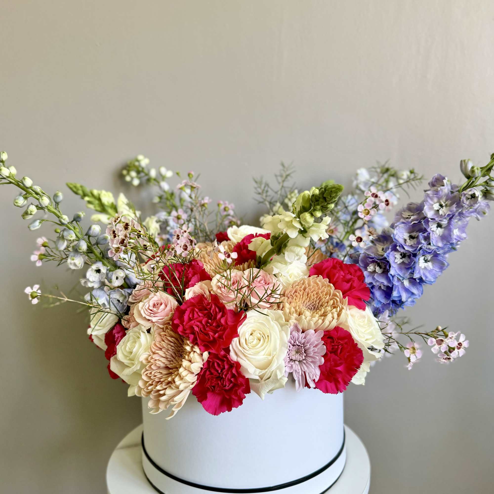 Colorful flower arrangement in a white hat box on a stand