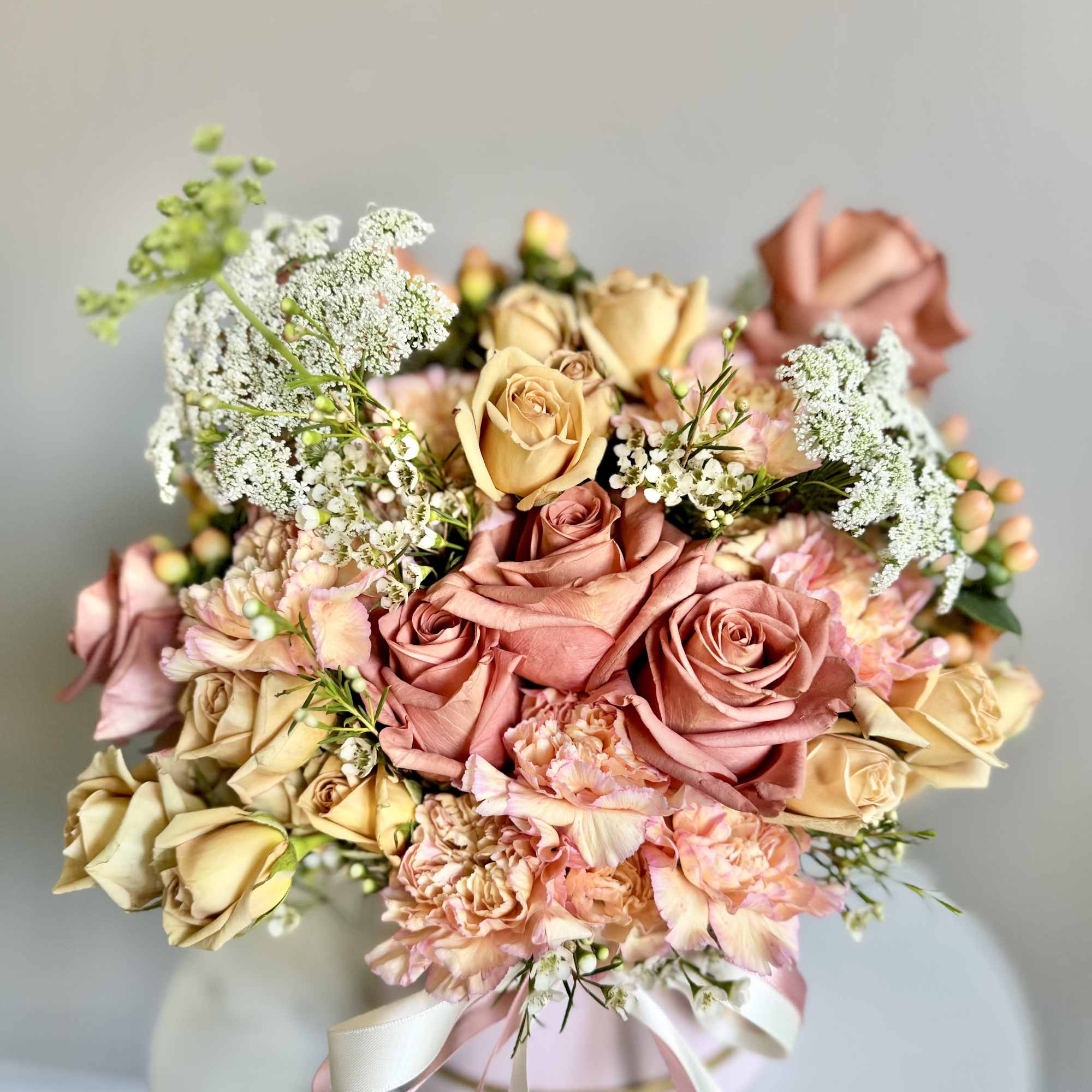 Bouquet of pink and cream roses with carnations and white filler flowers