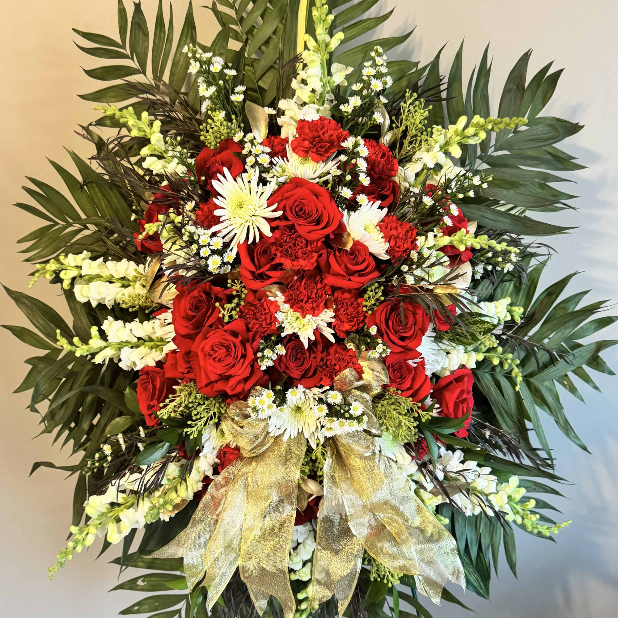 Large standing spray of red roses and white flowers with gold ribbon