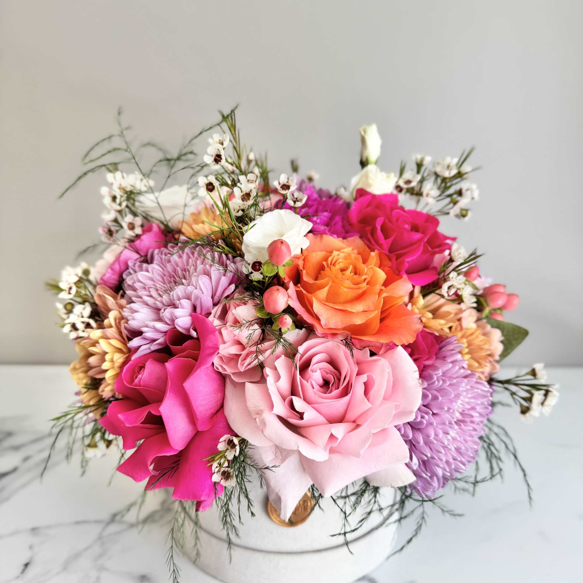 Bouquet of pink, orange, and purple flowers in a white hat box
