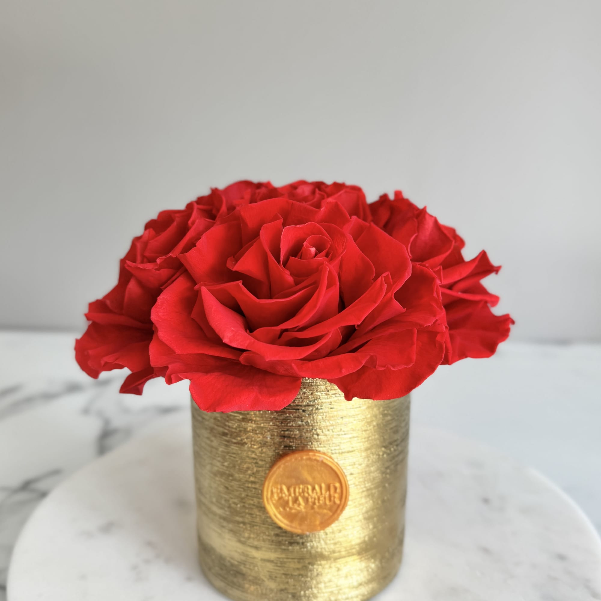 Red roses arranged in a gold cylindrical vase