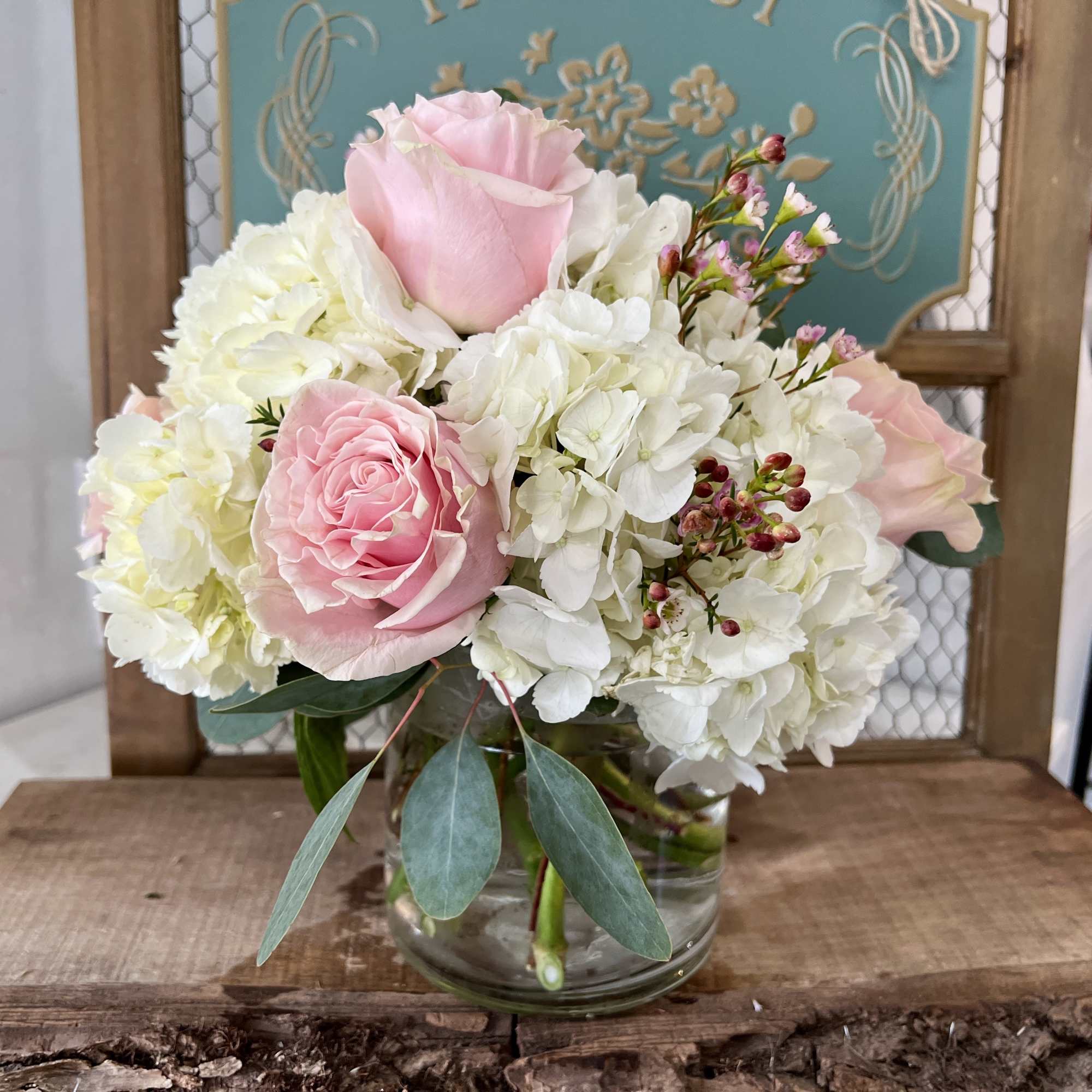 Pink roses and white hydrangeas arranged in a clear glass vase