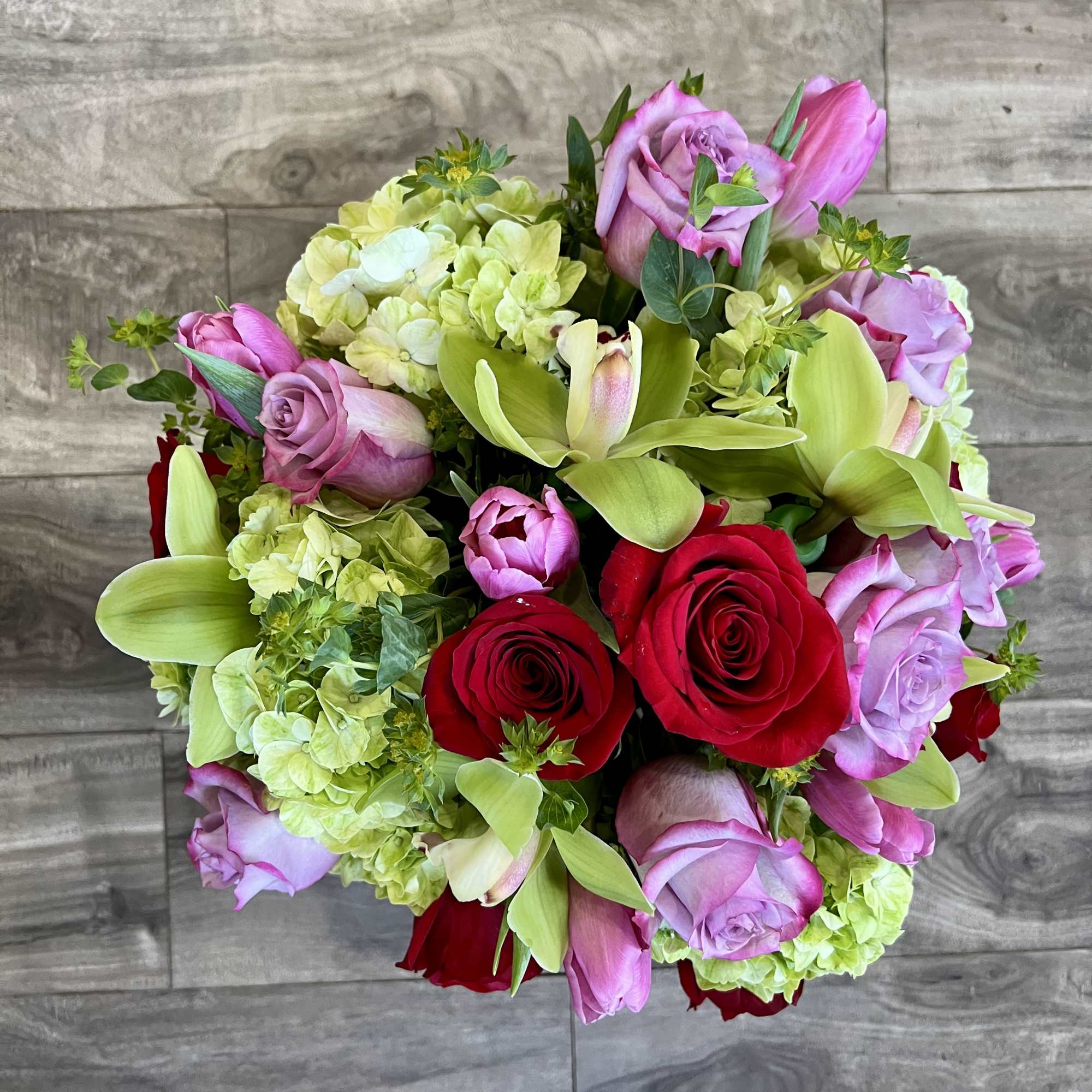 Green cymbidium orchids and hydrangeas, red roses and purple roses and tulips