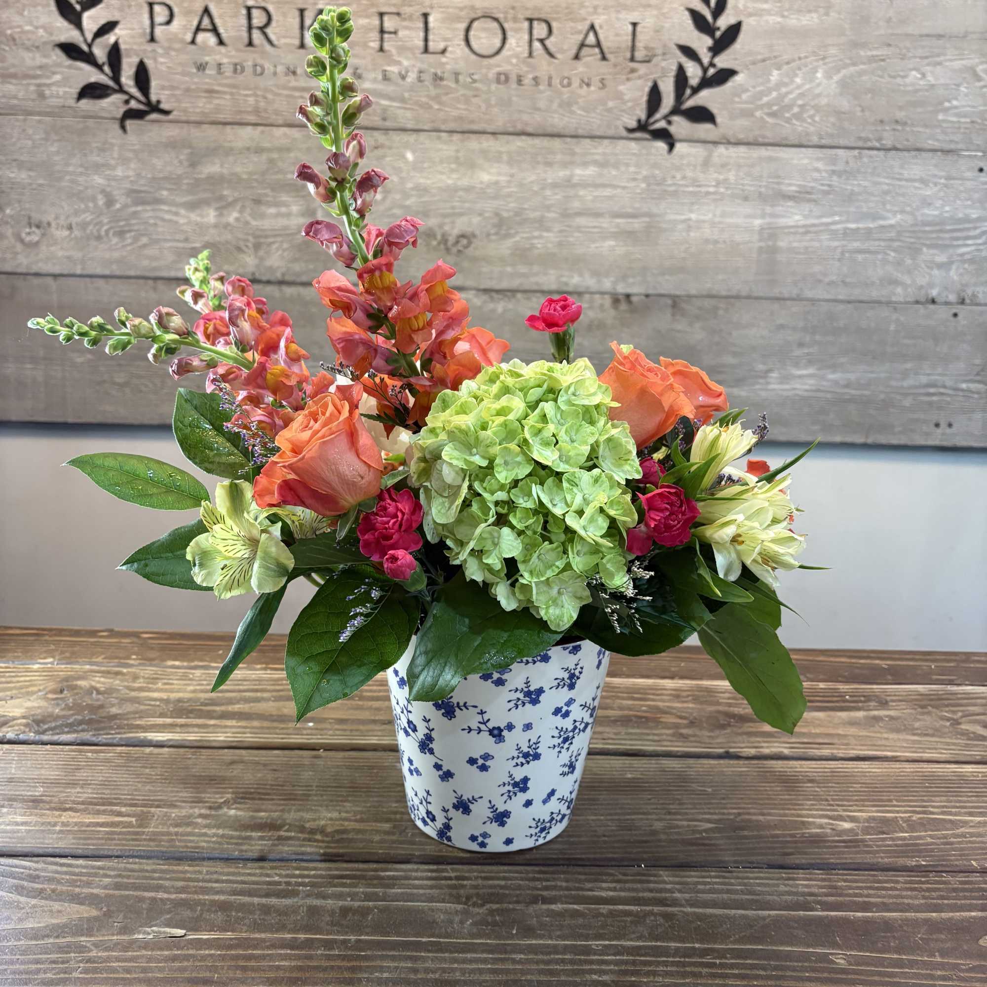 A lively cluster of coral-orange roses and bright green hydrangea makes an