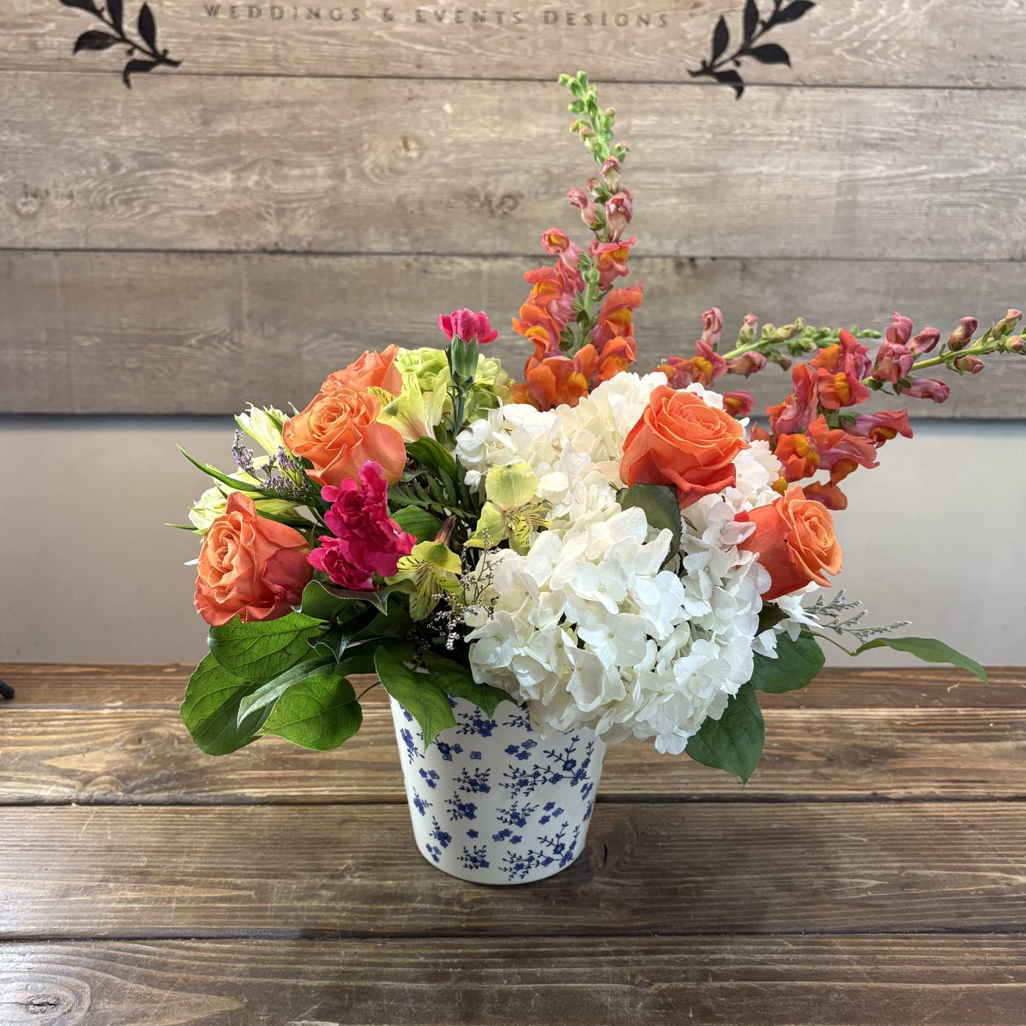 A lively cluster of coral-orange roses and bright green hydrangea makes an