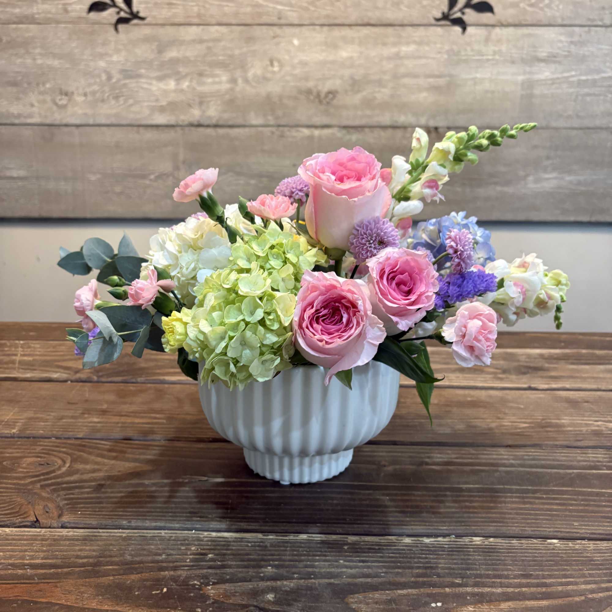Soft blush roses and pale green hydrangea create a gentle, garden-fresh centerpiece